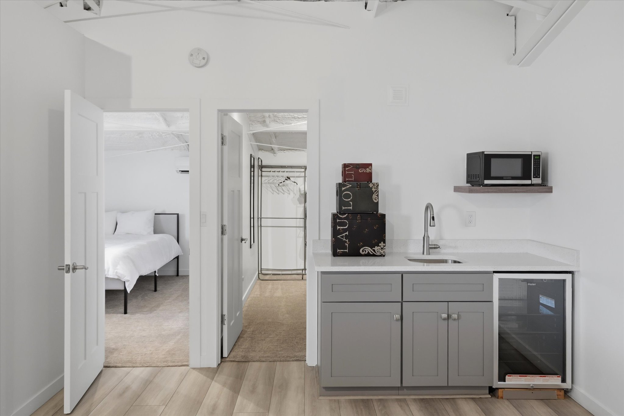 Compact kitchenette featuring gray cabinetry, a white countertop, a stainless steel sink, and a built-in beverage cooler