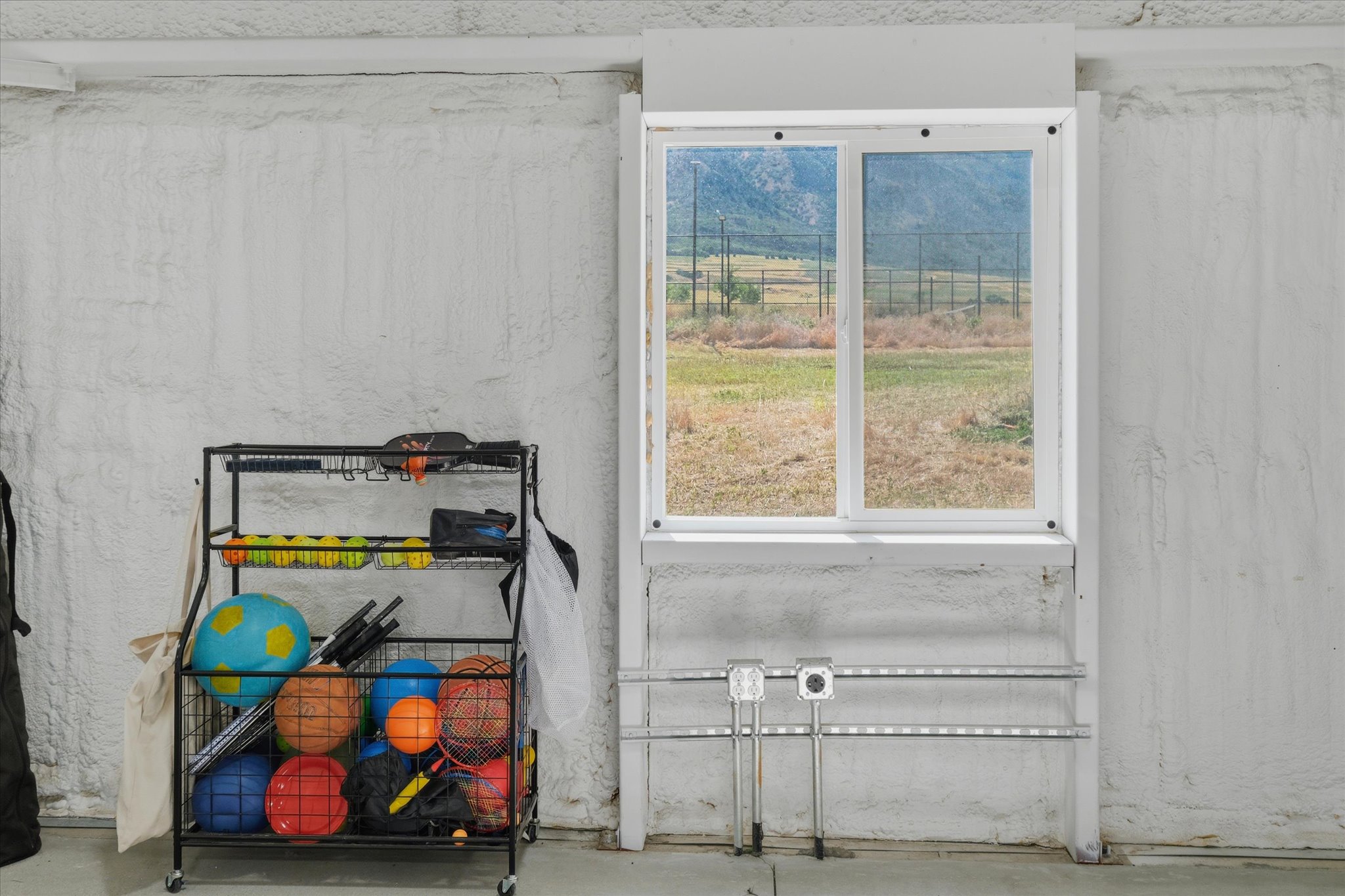 Dual-pane window with white frame, set within a textured white wall, offering a distant mountain landscape