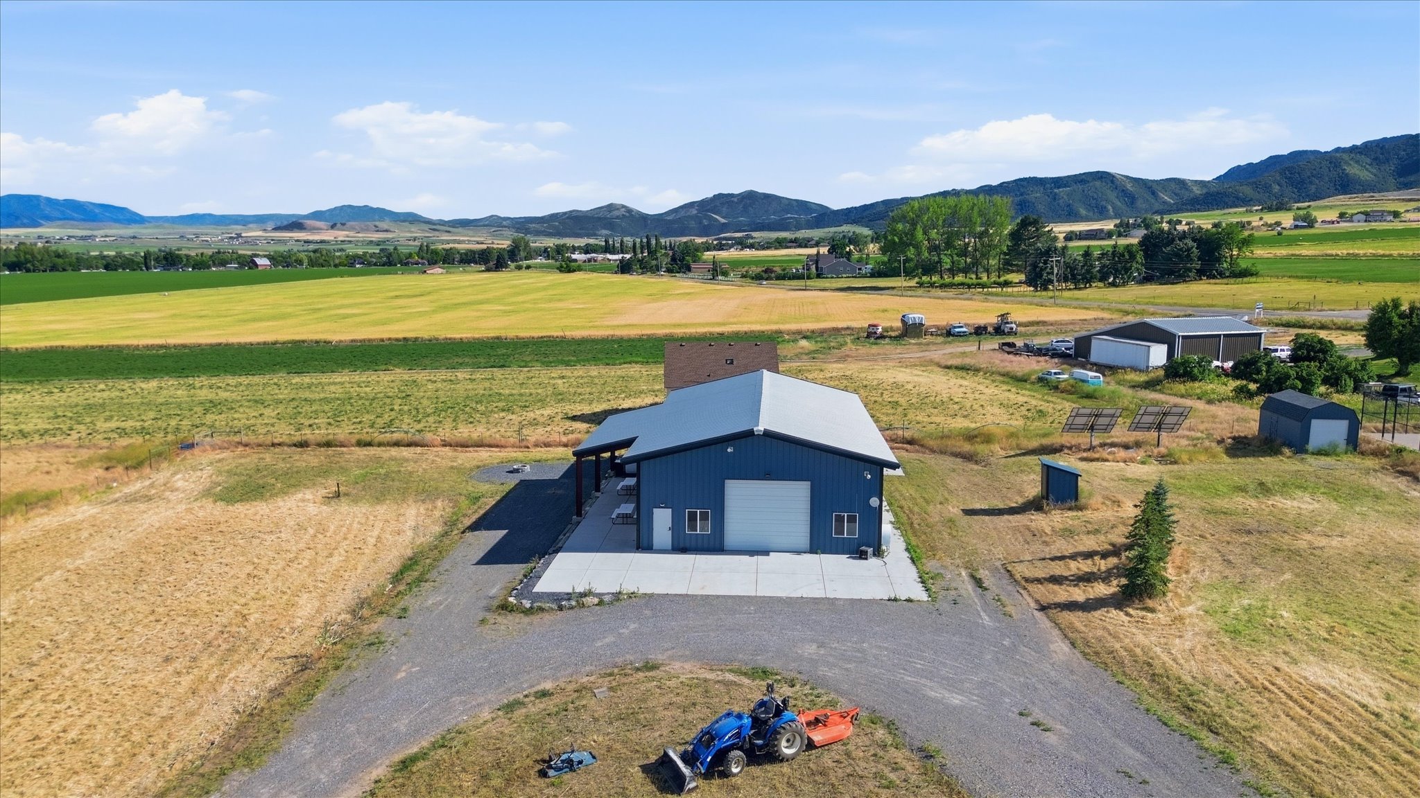 Blue metal-sided barn-style structure with a light gray roof and concrete apron