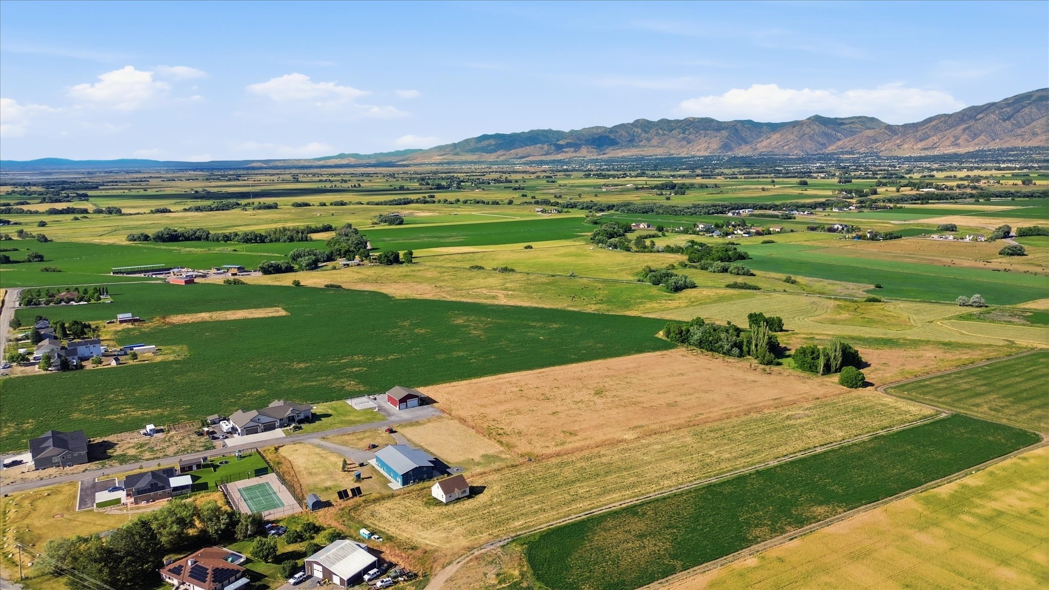 Expansive agricultural landscape featuring green fields, cultivated land, and distant mountains