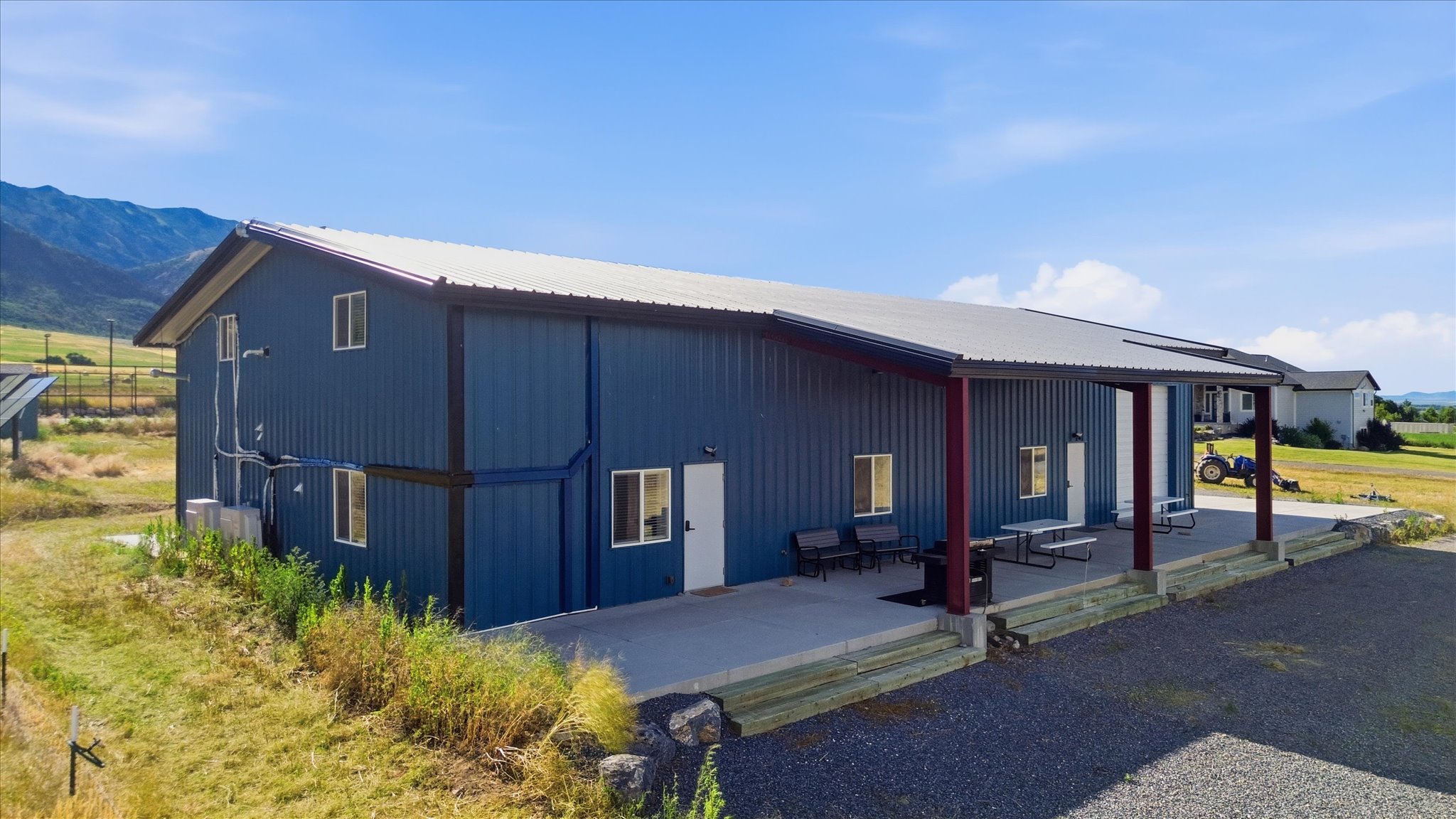 Contemporary blue metal building with a durable metal roof, featuring a covered concrete patio with exposed support beams