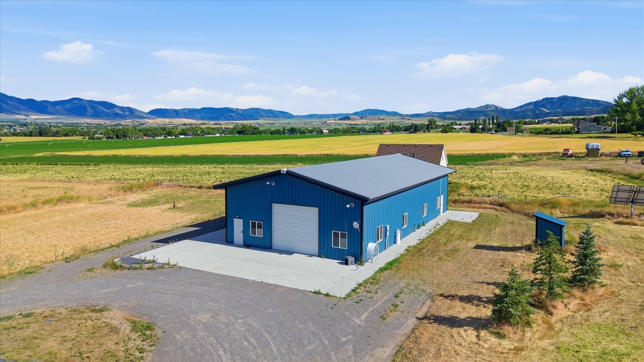 Blue metal-sided outbuilding with a gray roof and a large white garage door