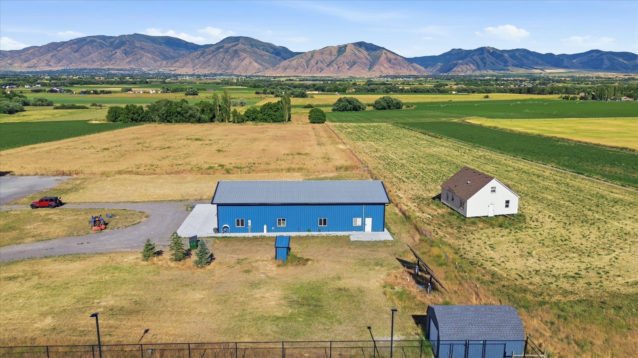 Expansive property featuring a blue metal-sided main building with a gray roof and a separate white gabled structure