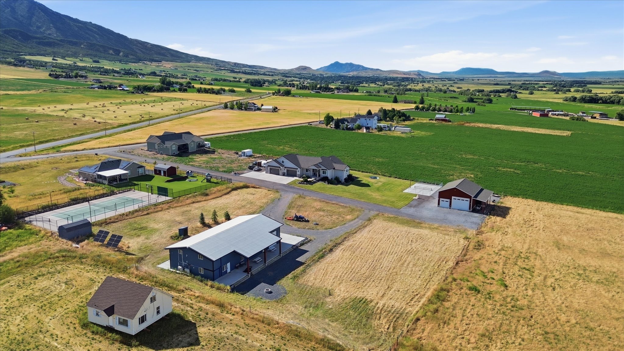 Expansive property featuring multiple structures, a private tennis court, and solar panel installations