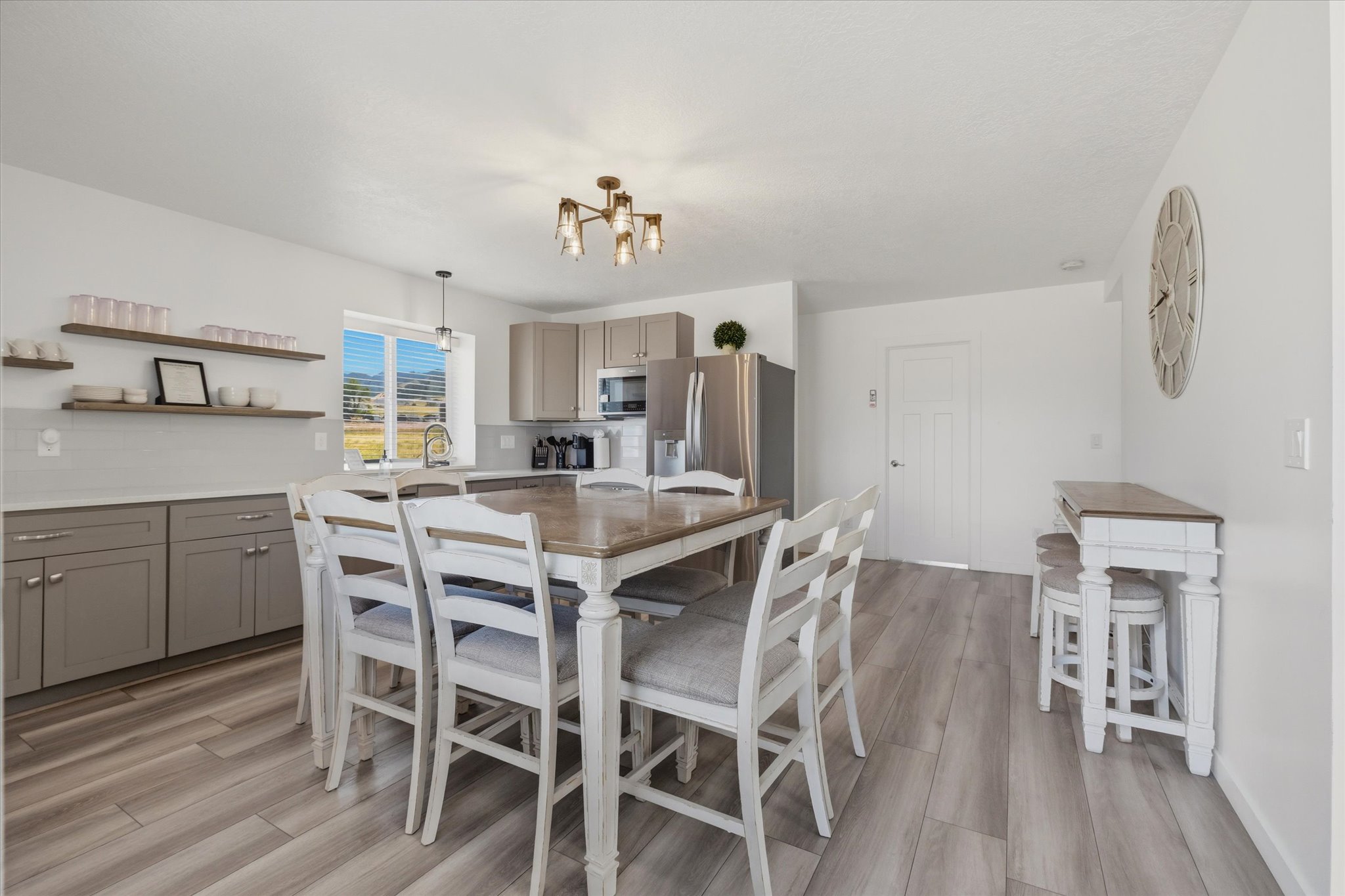 Open concept kitchen featuring light wood-finish flooring, a white subway tile backsplash, and light gray cabinetry