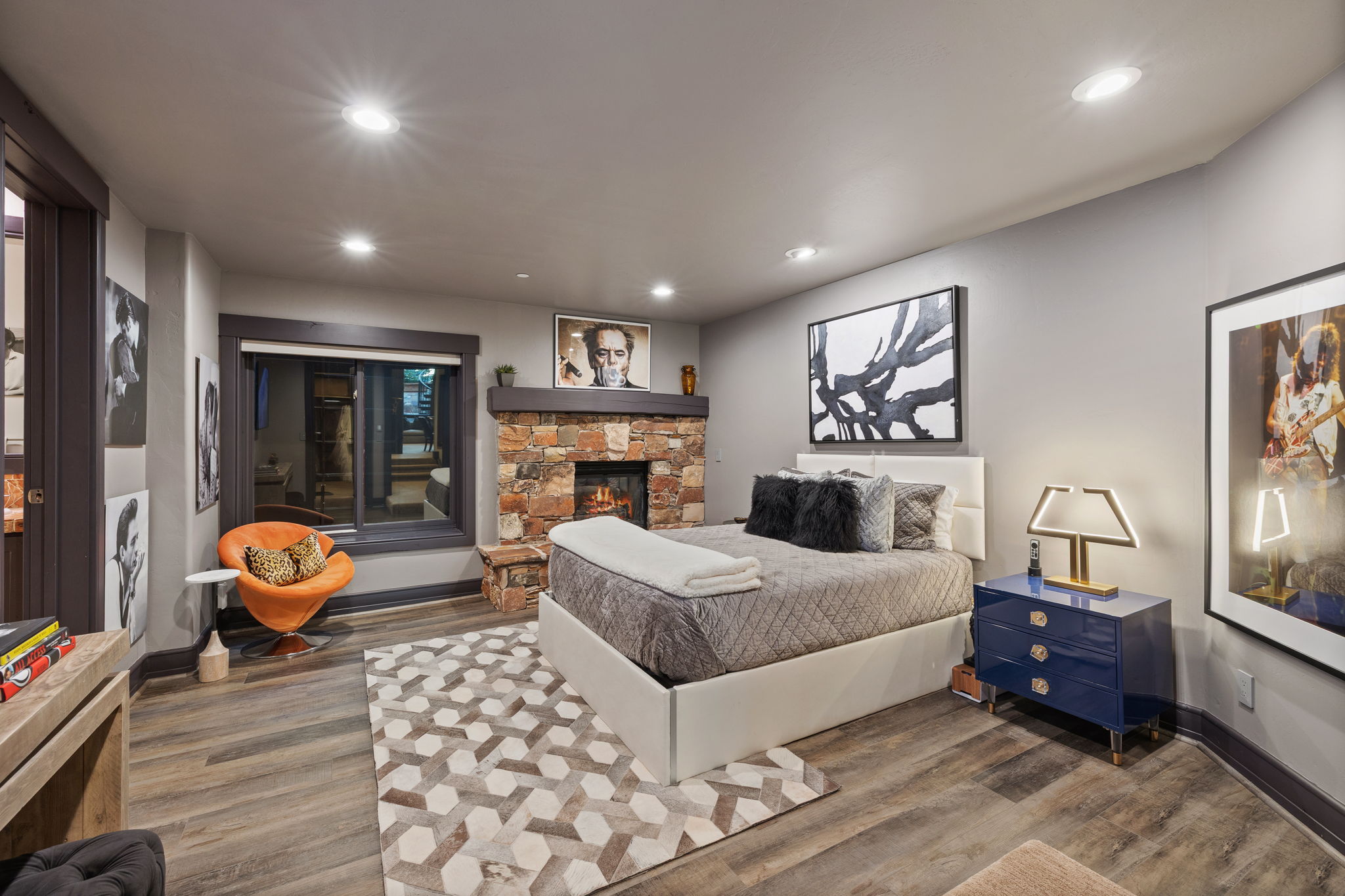 Bedroom featuring a stone fireplace with wood mantel, wood-finish flooring, recessed lighting, and a large window