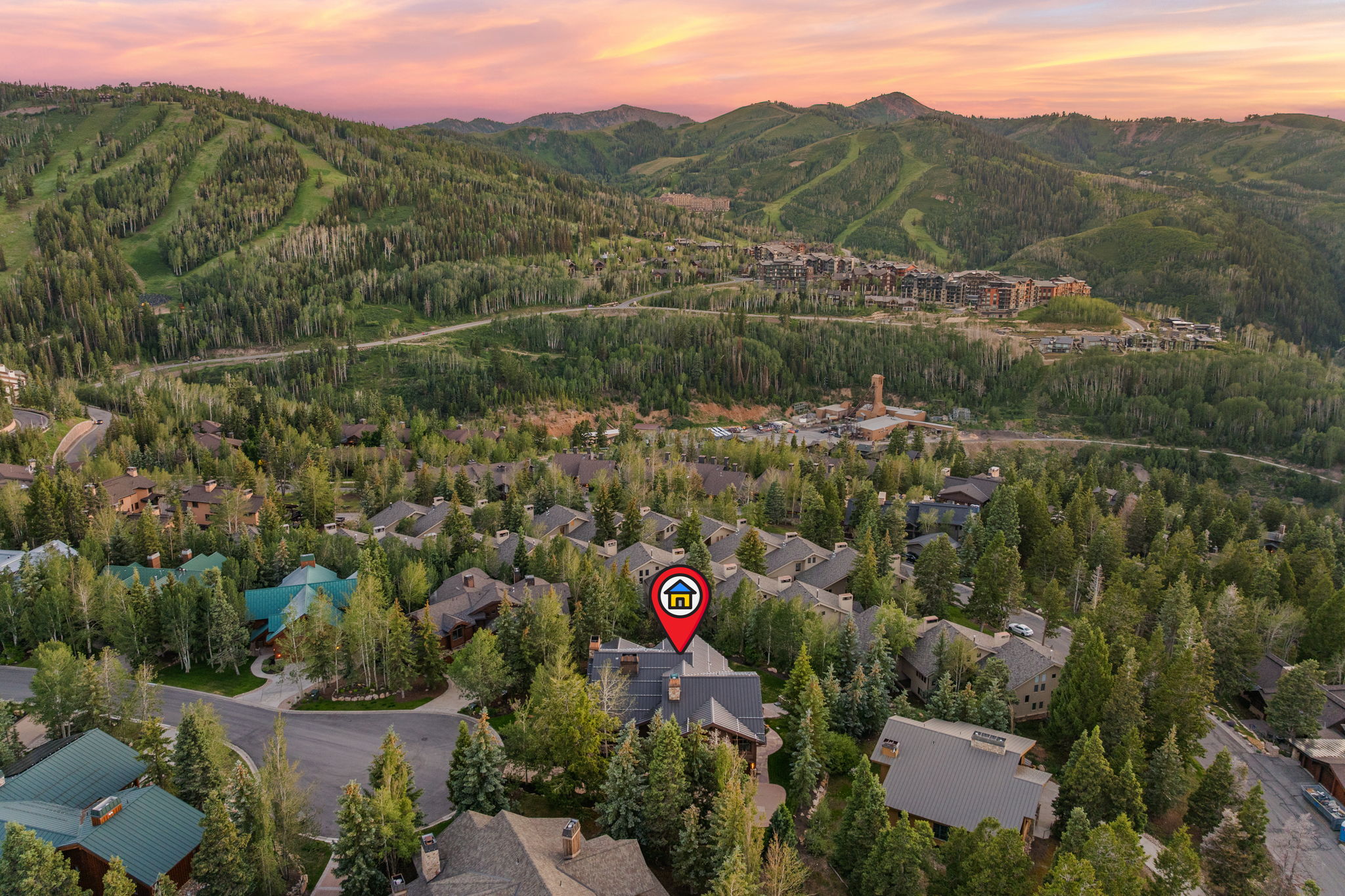 Aerial perspective showcasing a residential community nestled within a mountainous, heavily forested landscape