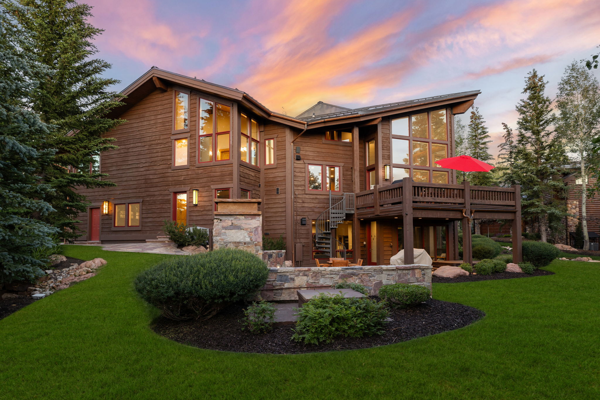 Expansive multi-level wood-clad residence featuring a spacious elevated deck with a spiral staircase