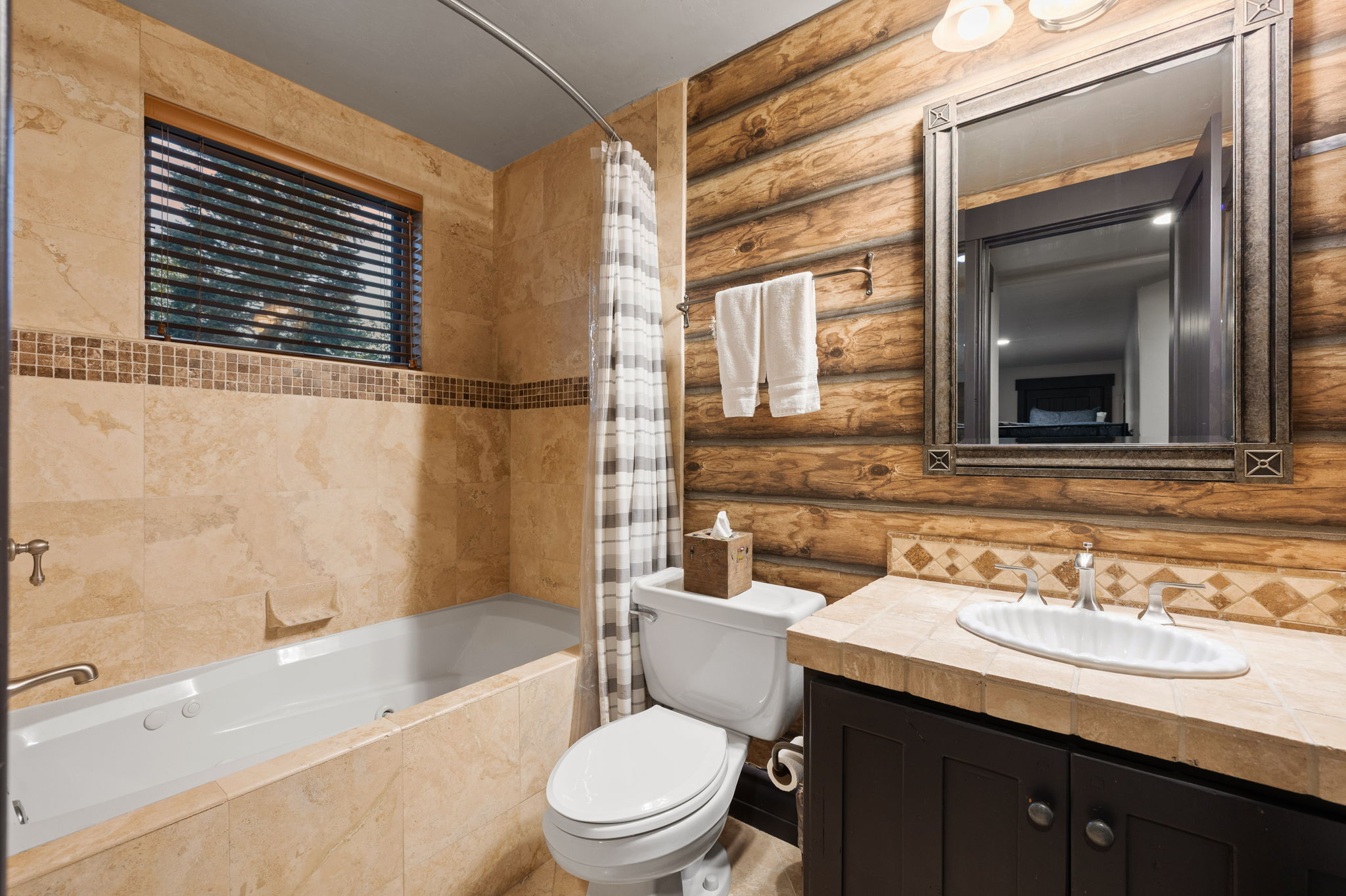 Bathroom featuring a jetted tub, a vanity with a dark wood-finish cabinet, and a tiled countertop