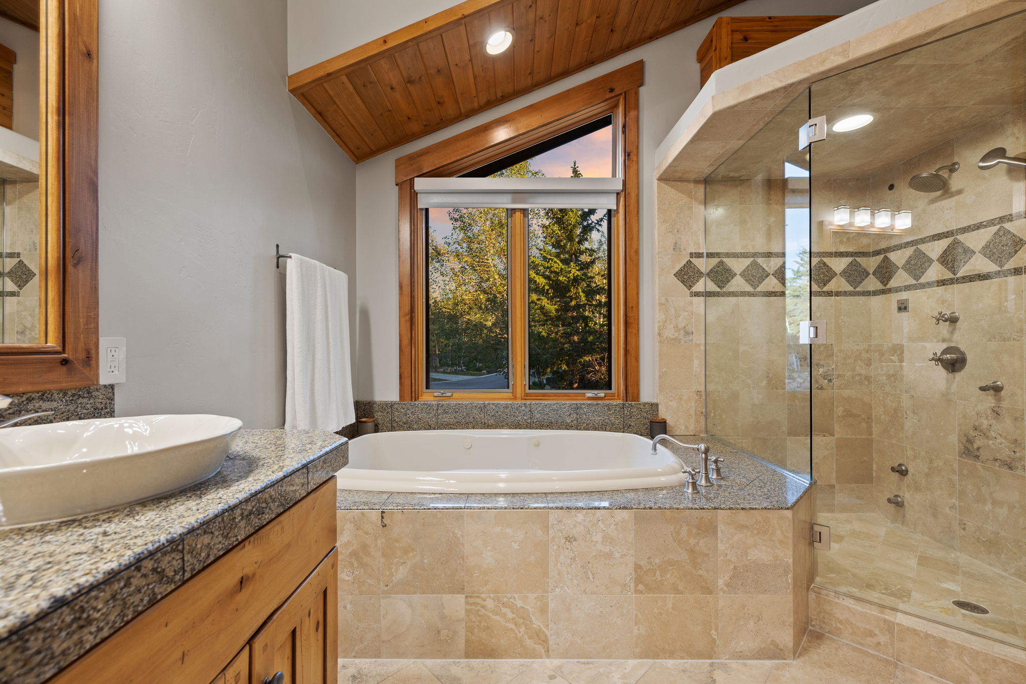 Bathroom featuring a soaking tub, glass-enclosed shower, and a wood-framed window