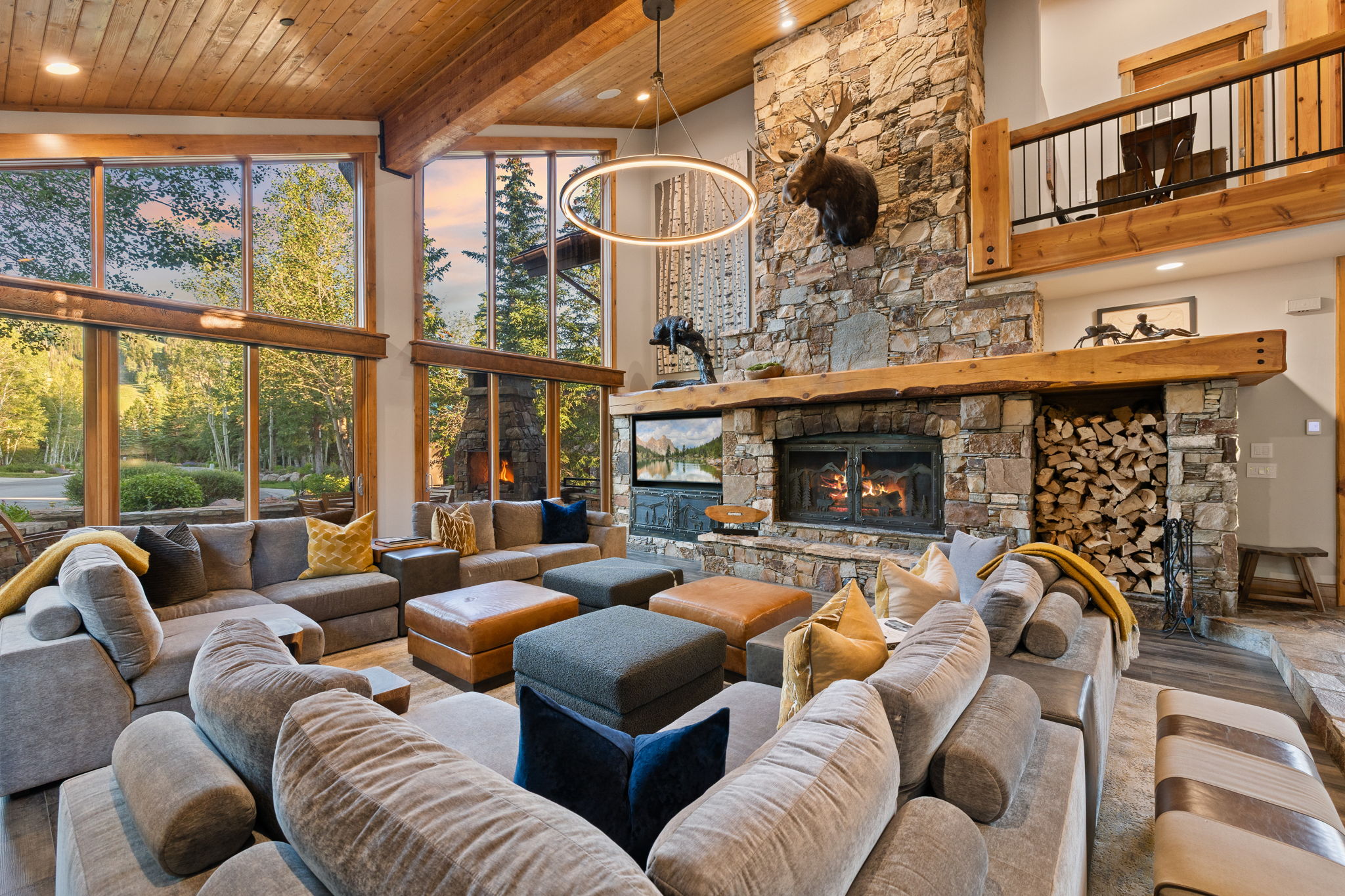 Expansive living area featuring a stone-clad fireplace with an integrated wood storage niche, a timber mantel, and a vaulted wood-paneled ceiling with exposed beams