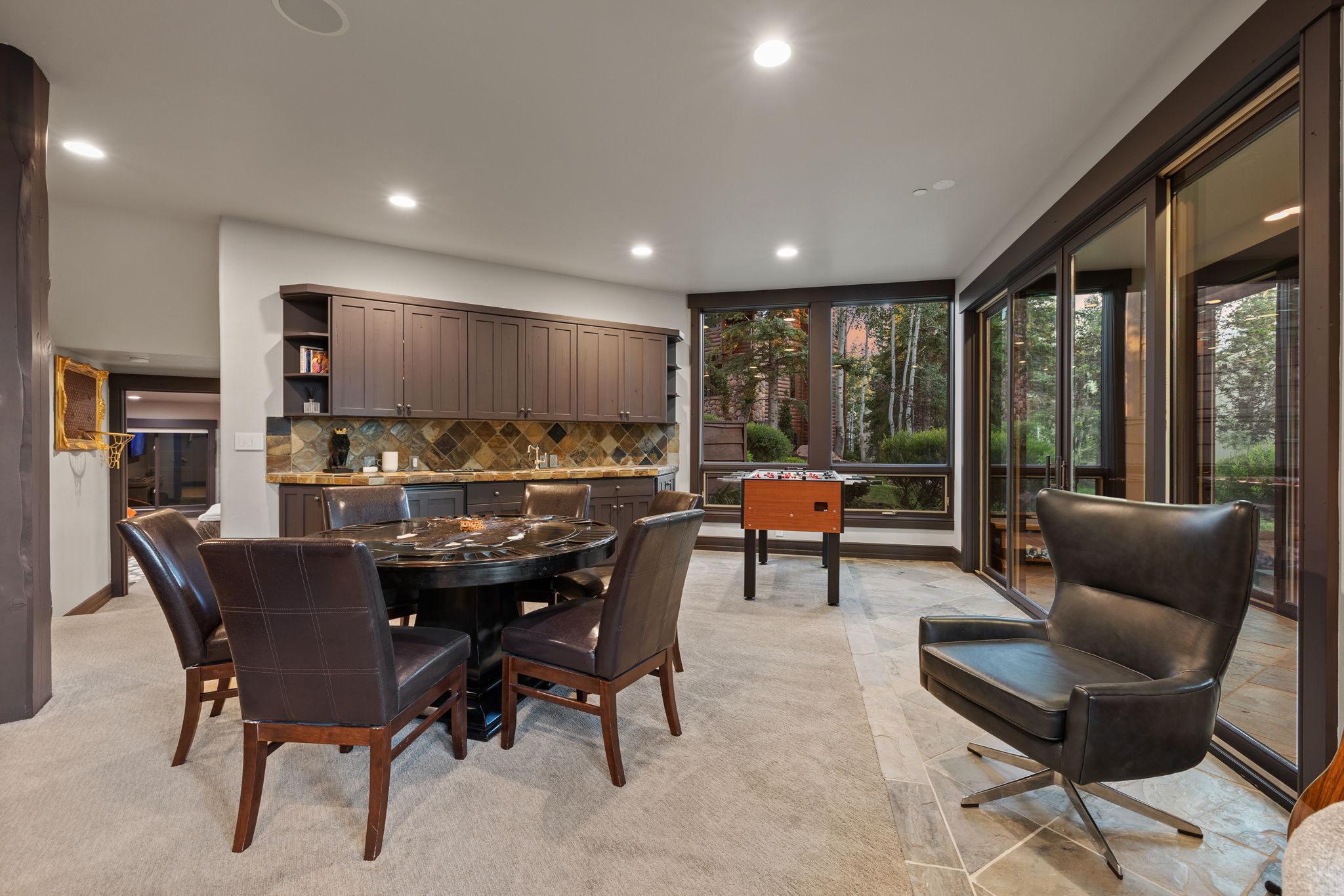 Recreational room with extensive built-in cabinetry, a stone backsplash, and recessed lighting