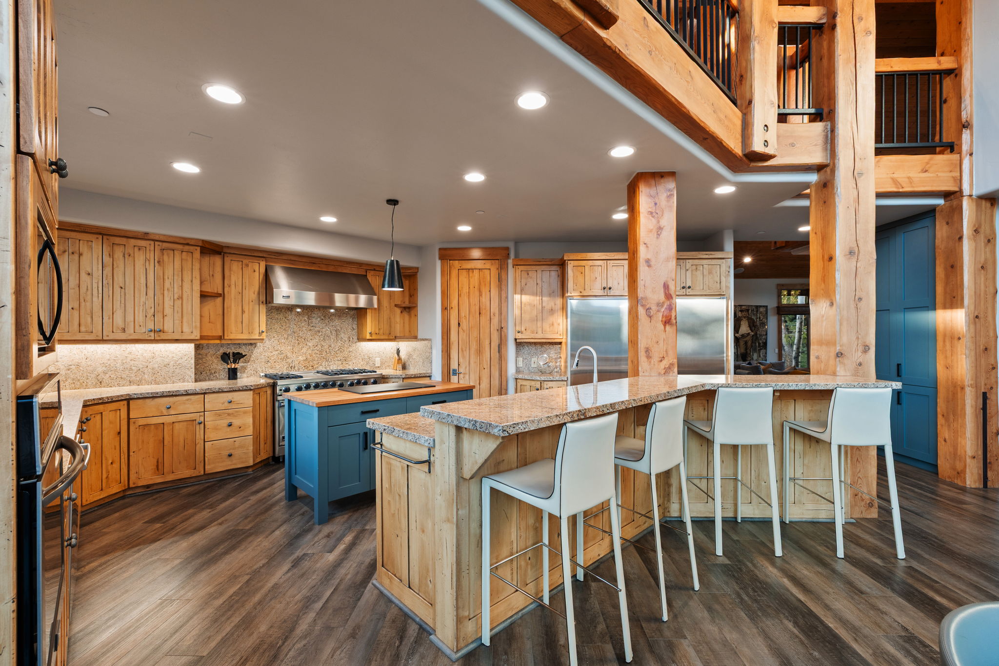 Gourmet kitchen featuring wood-finish flooring, custom wood cabinetry, a large central island with a wood countertop, and a breakfast bar with stone countertops