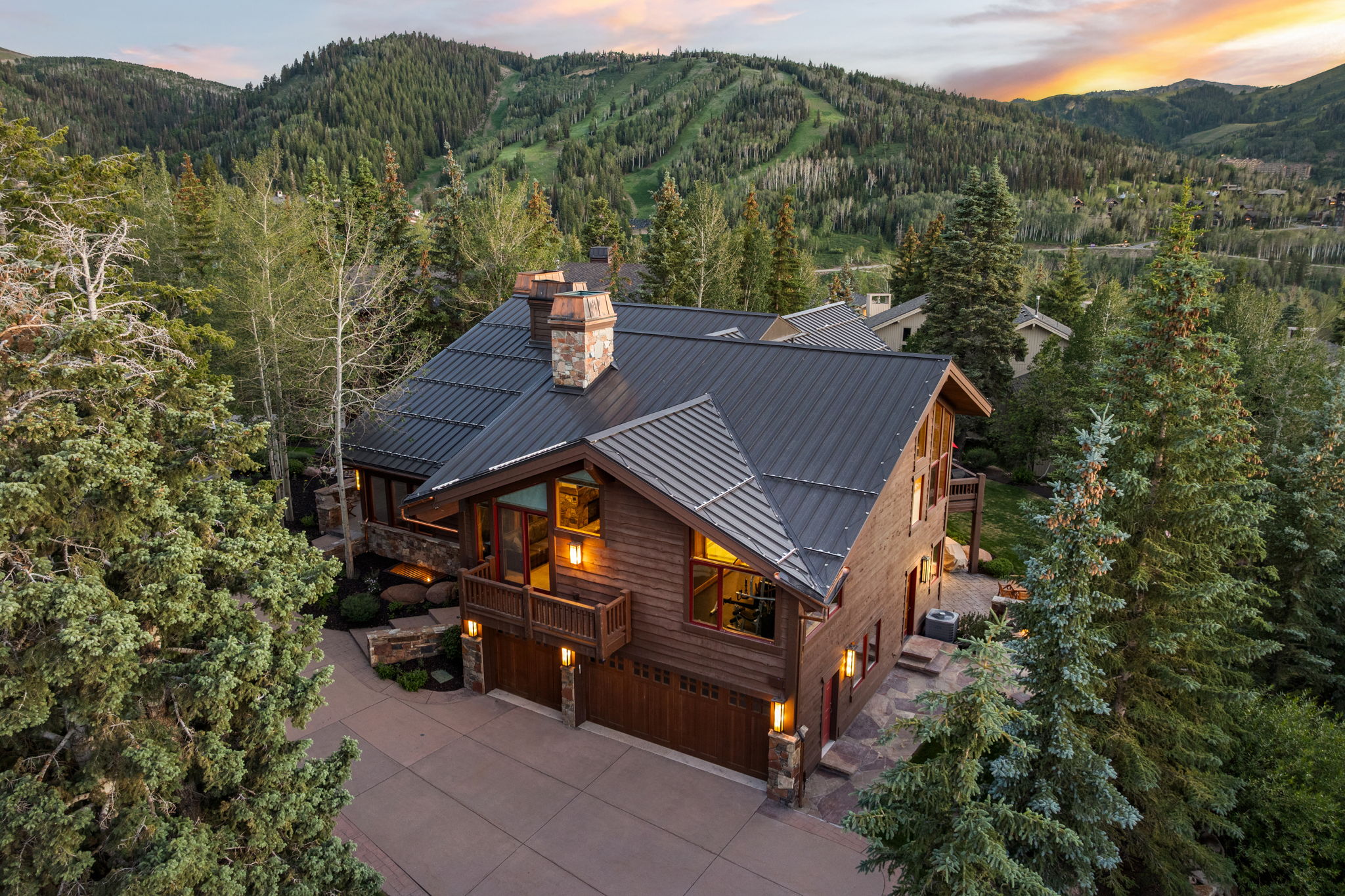 Mountain-style residence featuring a dark metal roof, wood siding, and stone accents