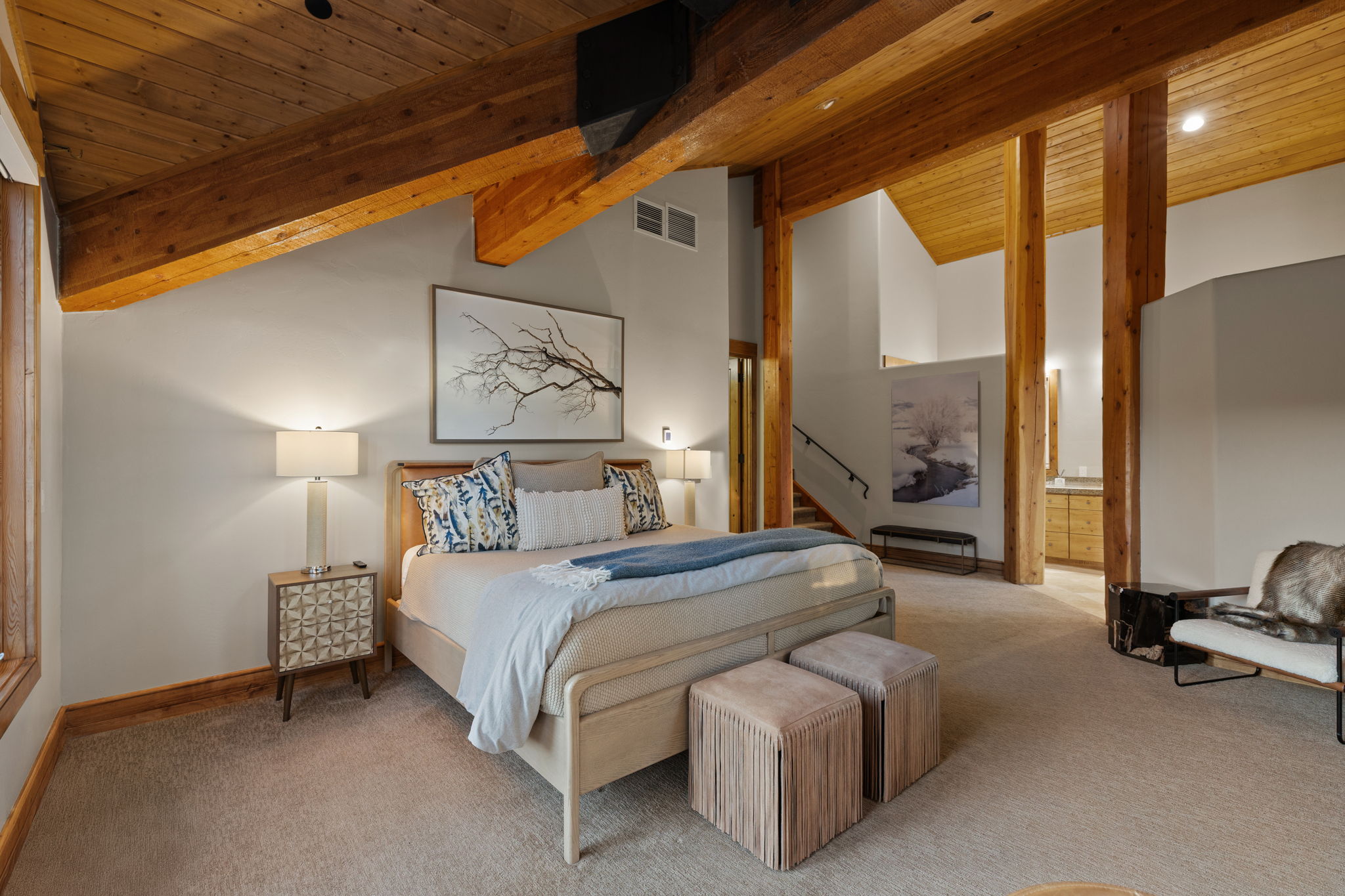 Spacious bedroom featuring exposed wood beams, vaulted ceilings, and plush carpet flooring
