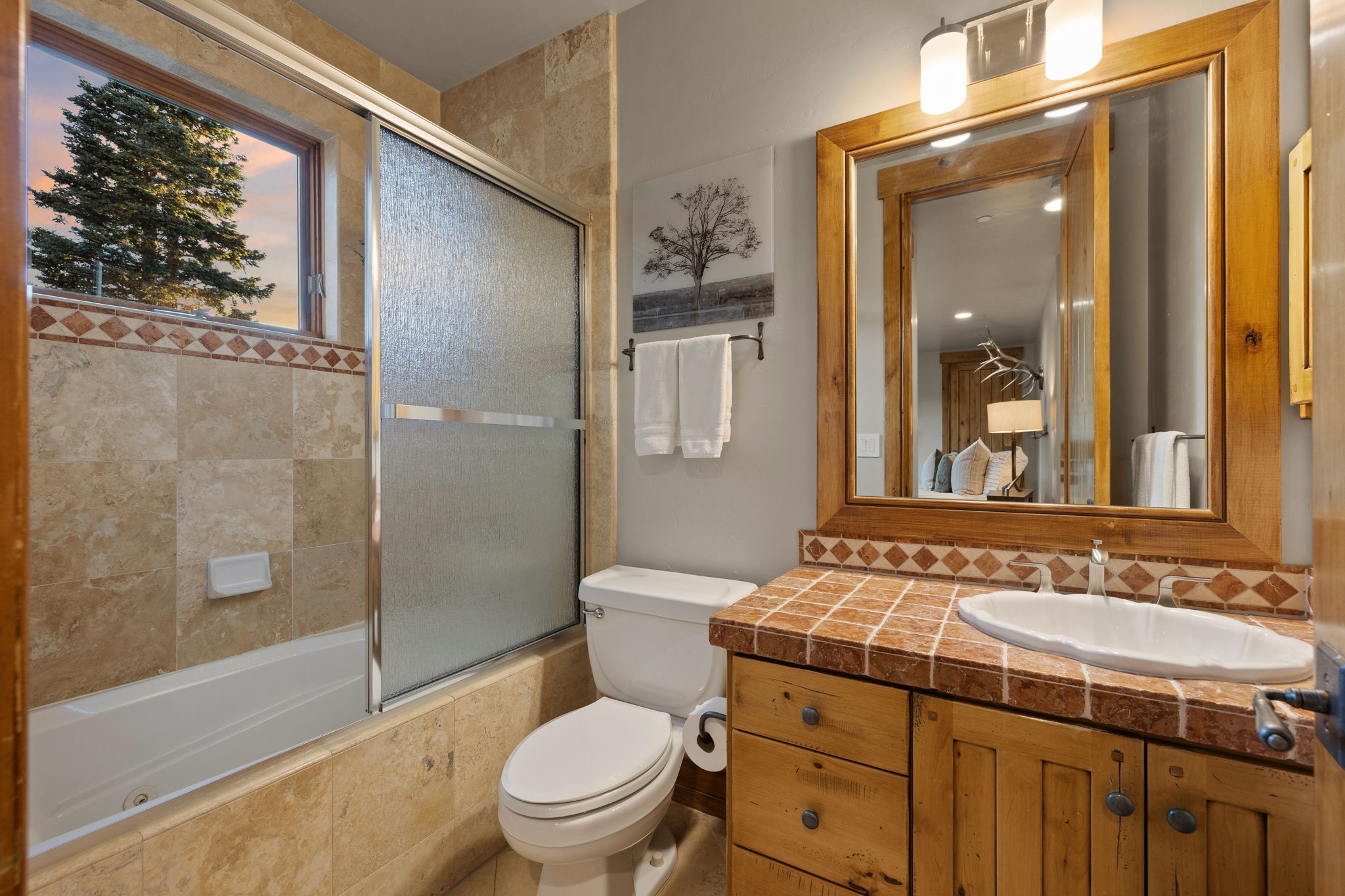 Bathroom featuring a wood-framed mirror, wood vanity with tiled countertop, and an integrated sink