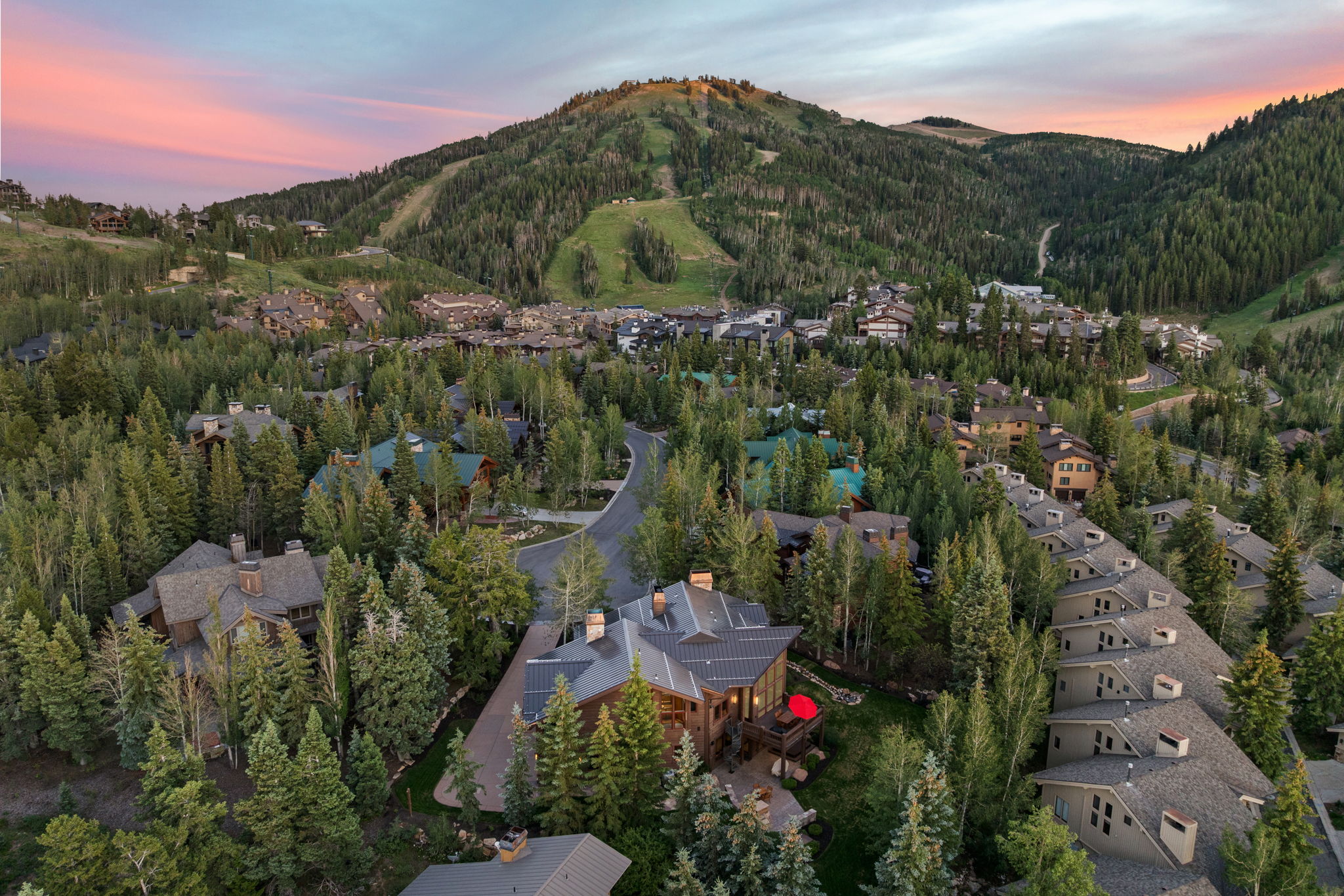 Expansive mountain property featuring a multi-level residence with a wood-finish exterior, surrounded by mature evergreen trees
