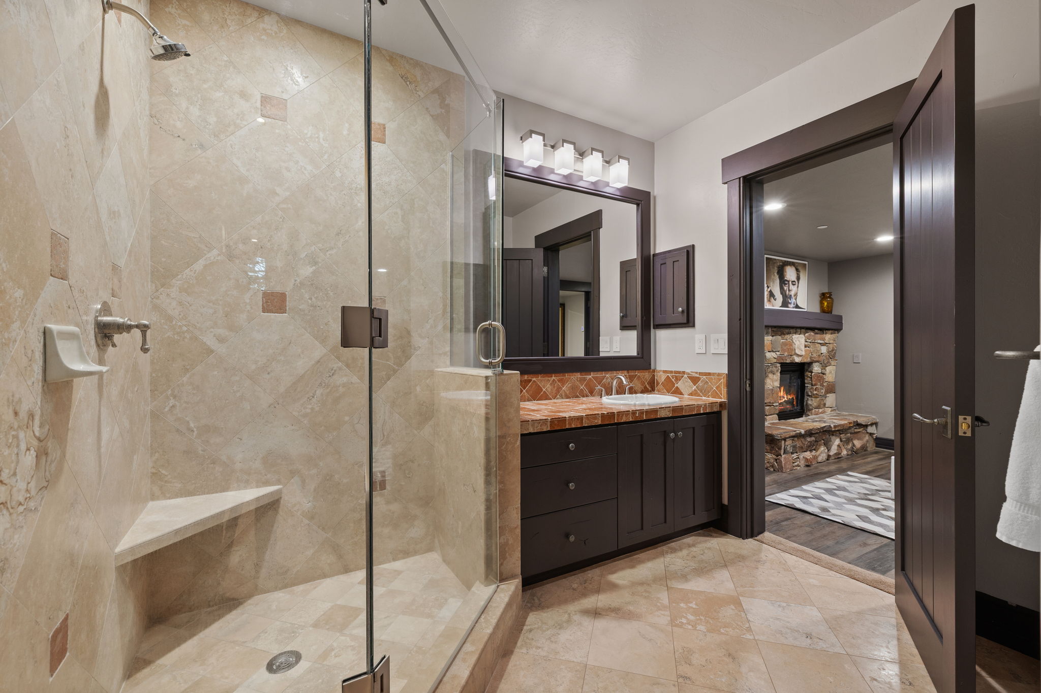 Walk-in shower with full height tile surround, integrated corner bench, and glass enclosure