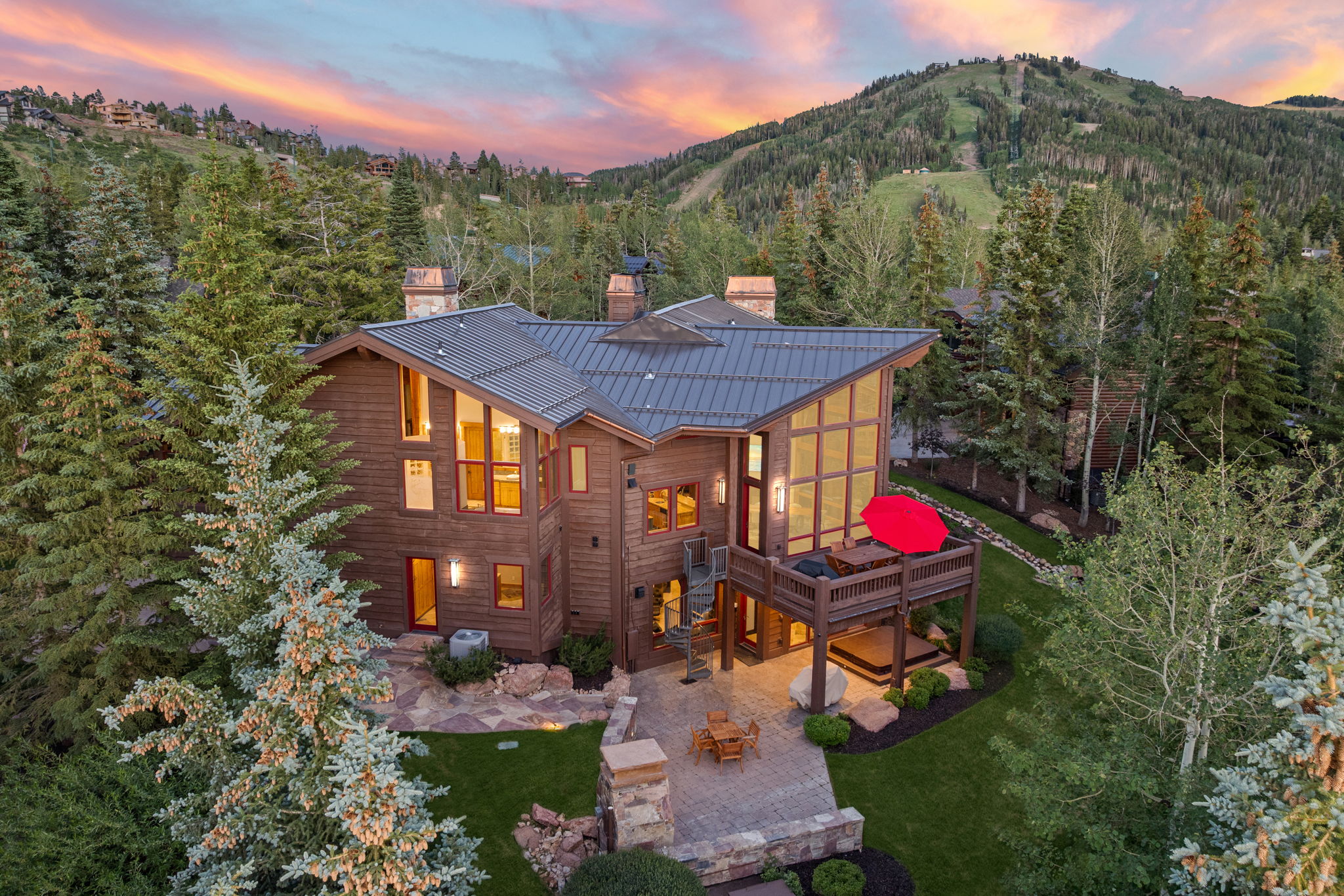 Cedar-sided mountain home featuring a metal roof, extensive decking, and a stone patio