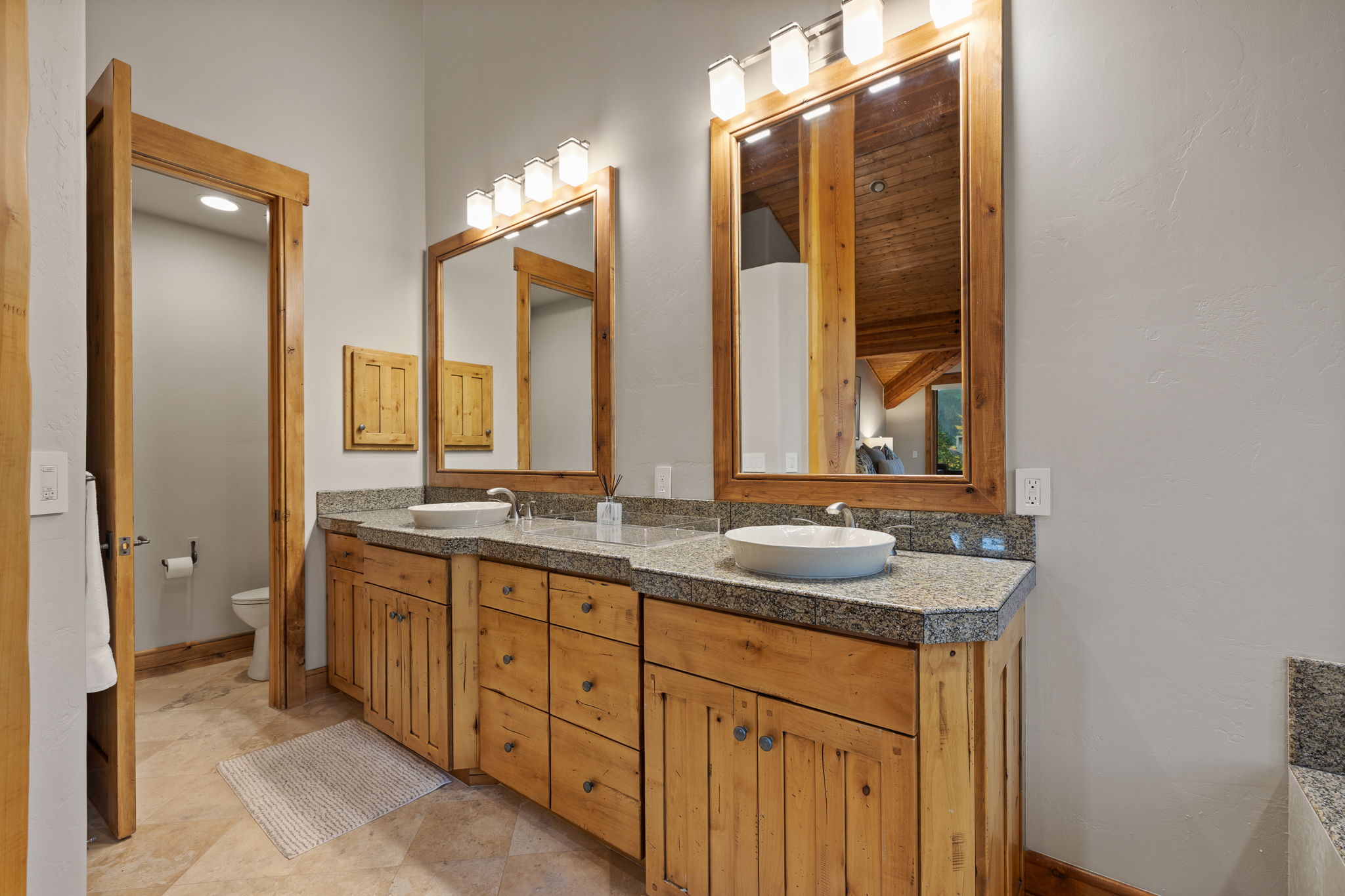 Double vanity featuring wood cabinetry, vessel sinks, and stone countertops