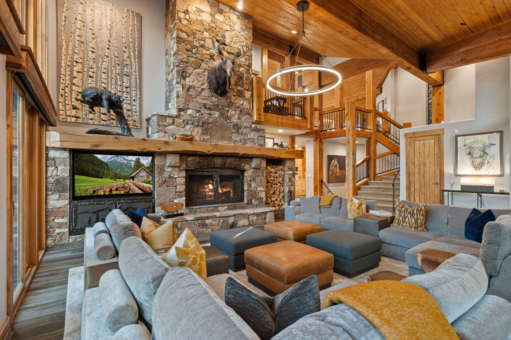 Spacious living area featuring a prominent stone fireplace, wood-beamed ceilings, and wood-finish flooring