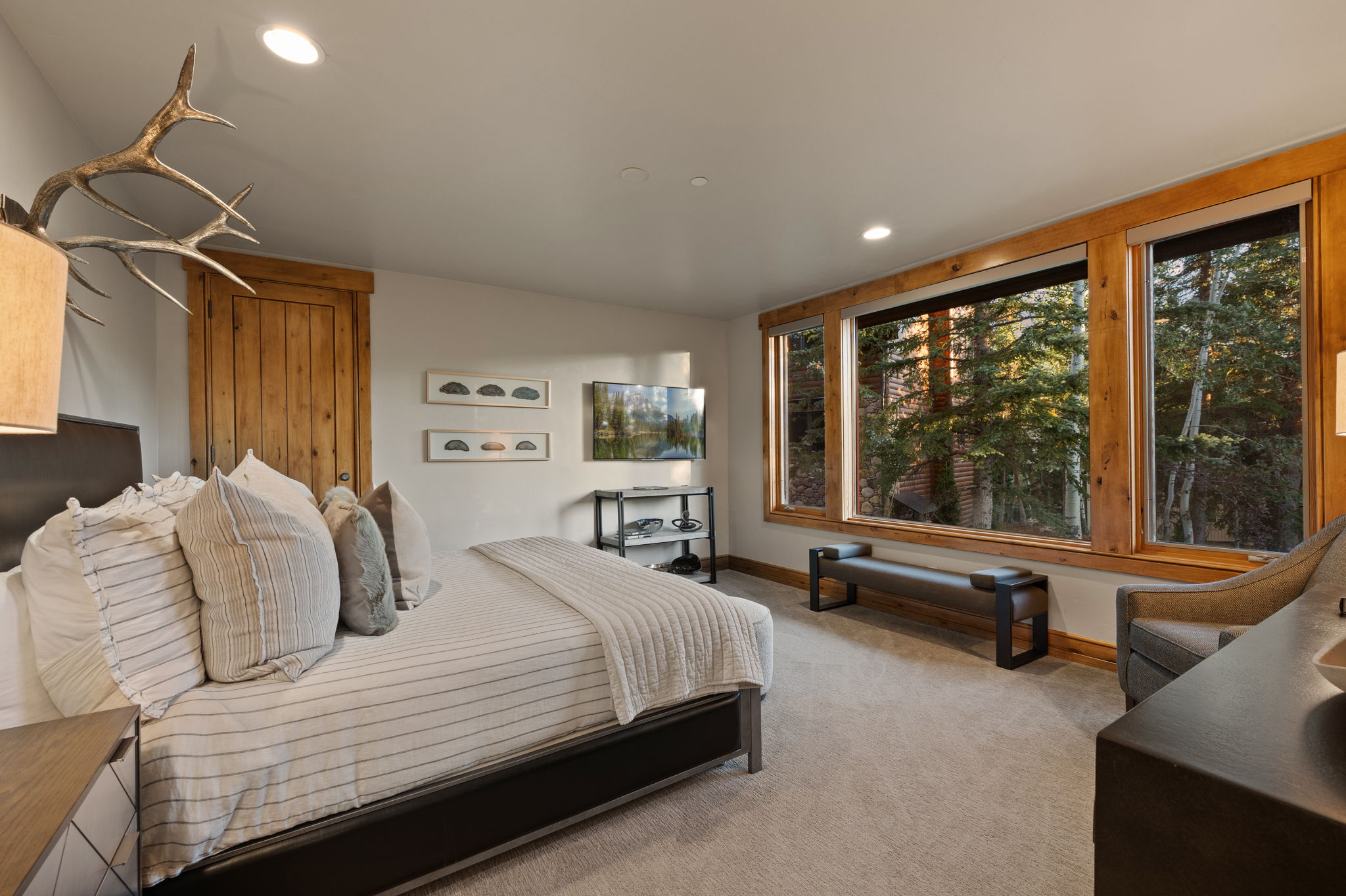 Bright room featuring large windows with wood framing, recessed lighting, a built-in wood door, and carpet flooring
