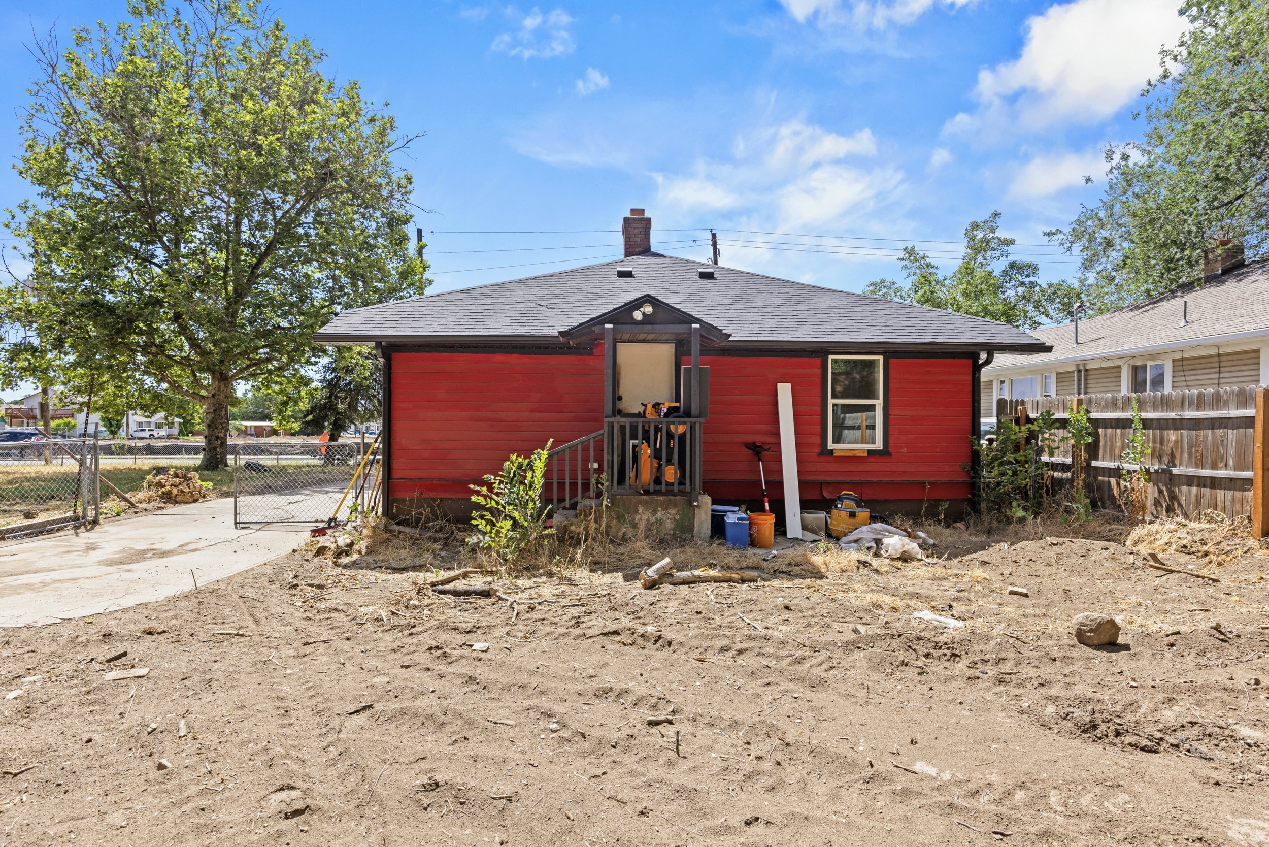 Red exterior siding with dark trim, featuring a dark shingle roof and a rear entry porch with railings