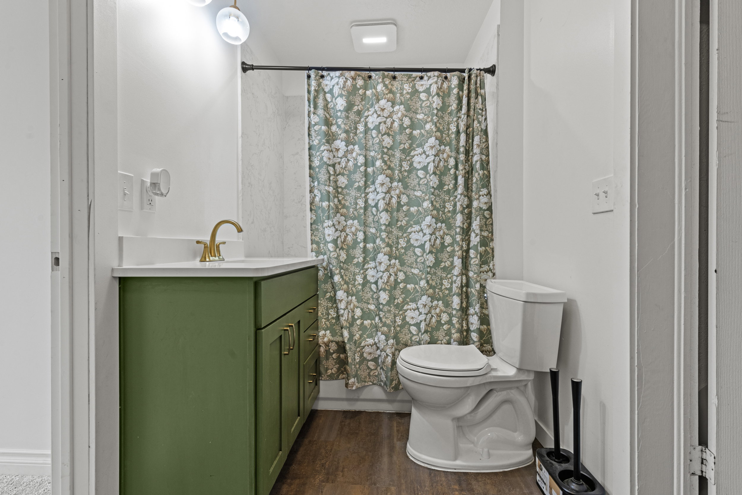 Bathroom featuring a green vanity with brass-finish hardware, white countertop, and brass-finish faucet