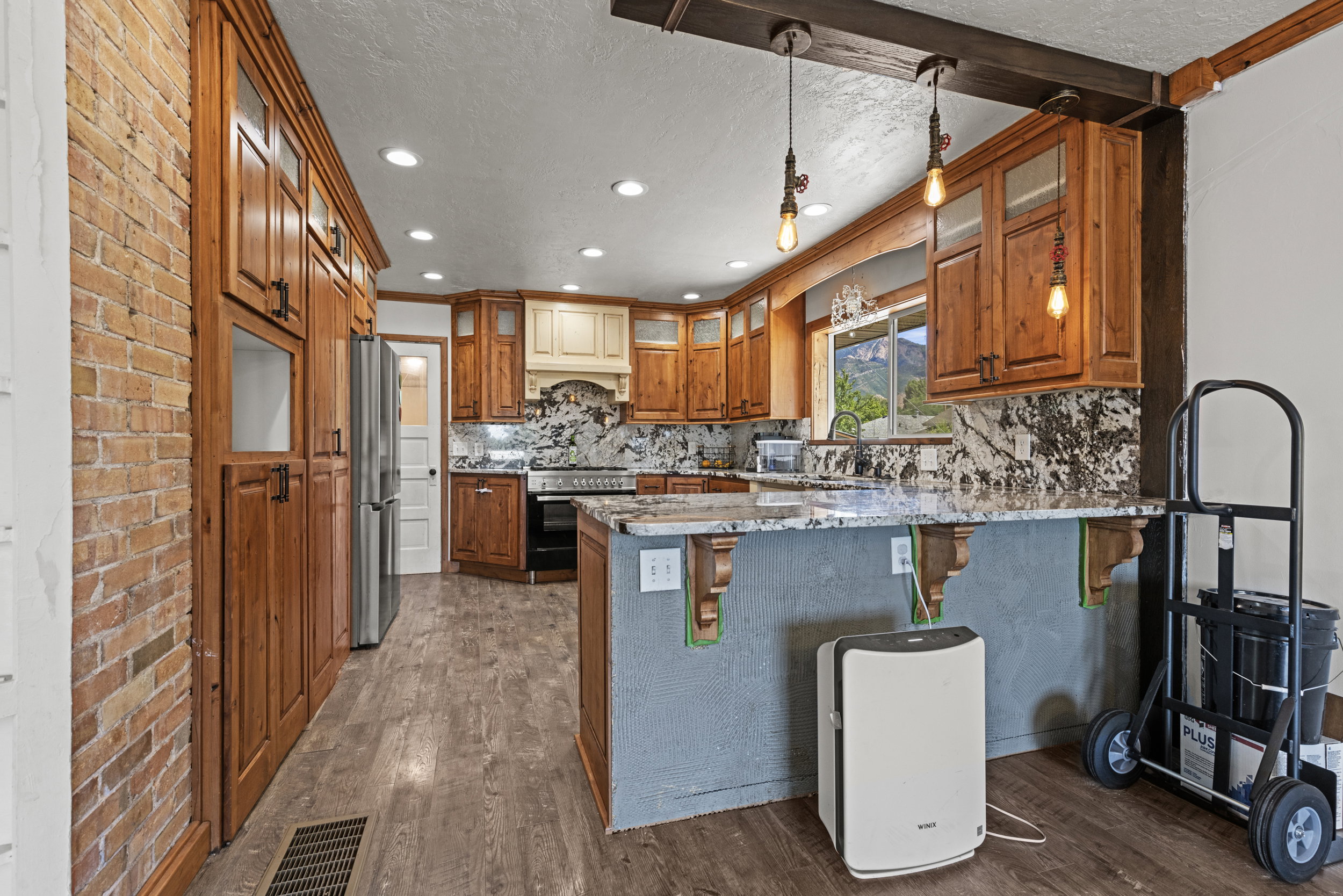Kitchen featuring wood-finish cabinetry, stone countertops, and a stone backsplash