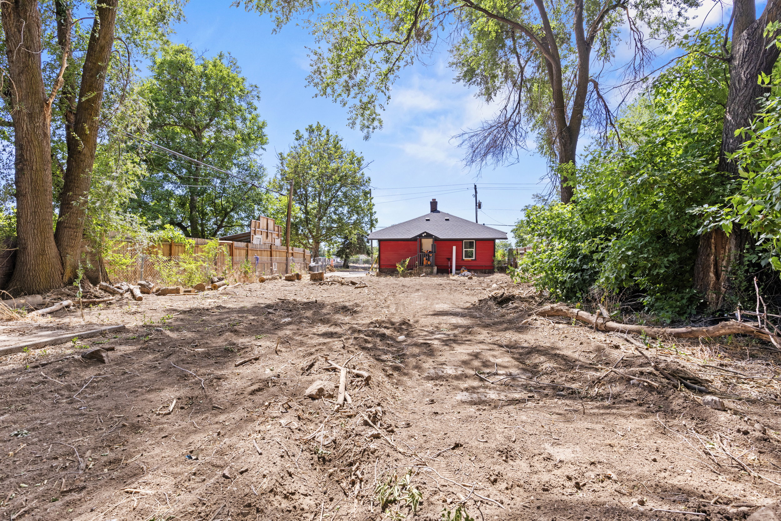 Expansive cleared lot with mature trees, offering a red exterior structure with a dark roofline