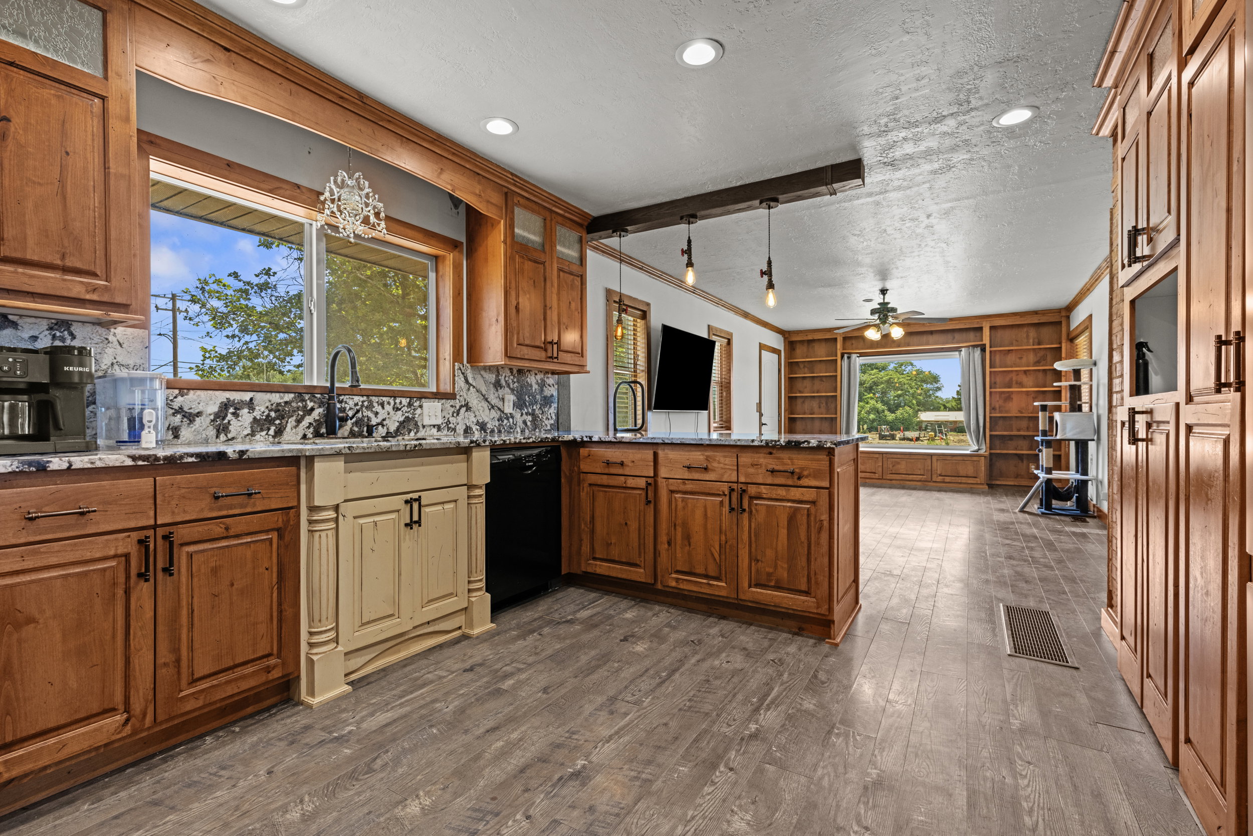 Kitchen featuring wood-finish flooring, dark perimeter countertops with a coordinating backsplash, and an island with a contrasting countertop