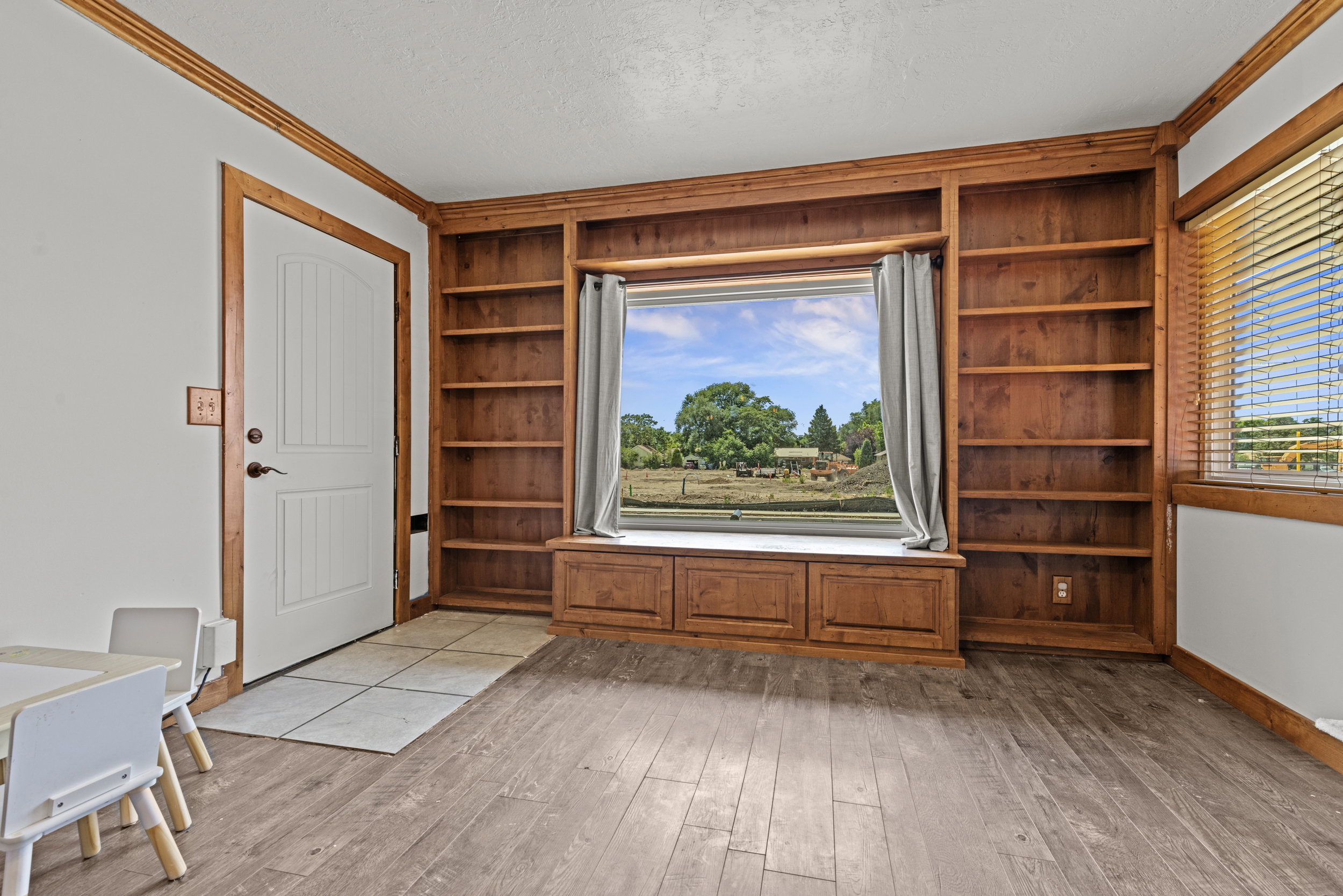 Built-in wood-finish shelving surrounding a window seat with storage