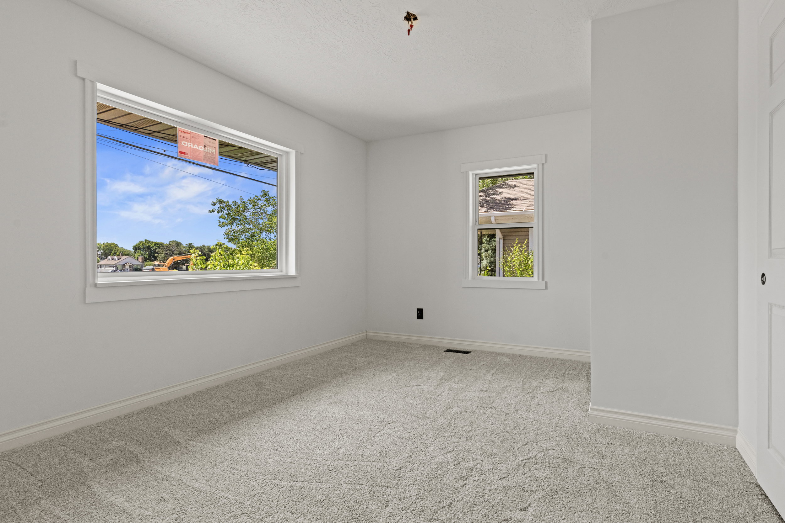 Carpeted interior room featuring light gray walls, two windows with white trim, and white baseboards
