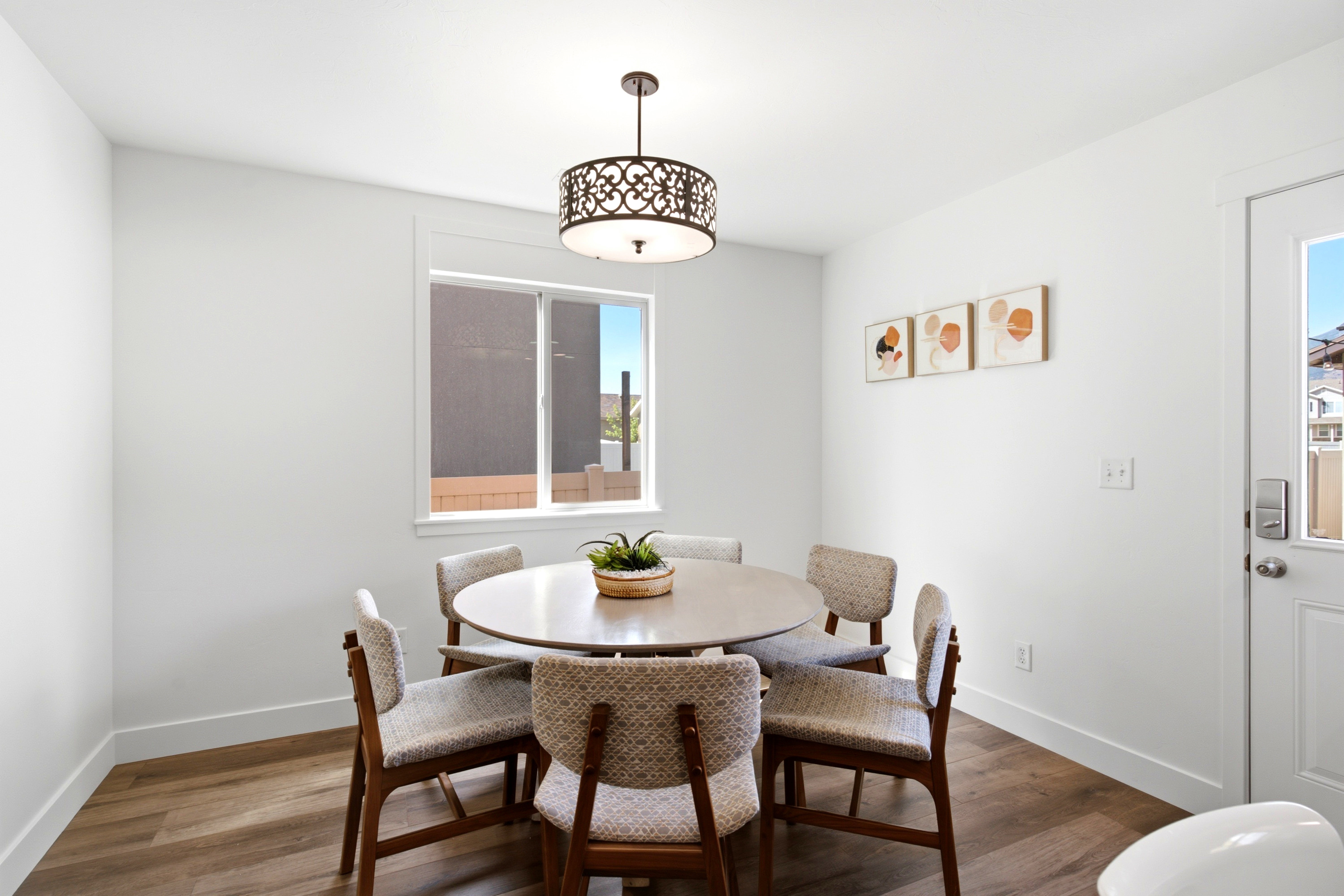 Bright dining area featuring wood-finish flooring, a contemporary chandelier, a white window frame, and a paneled white door