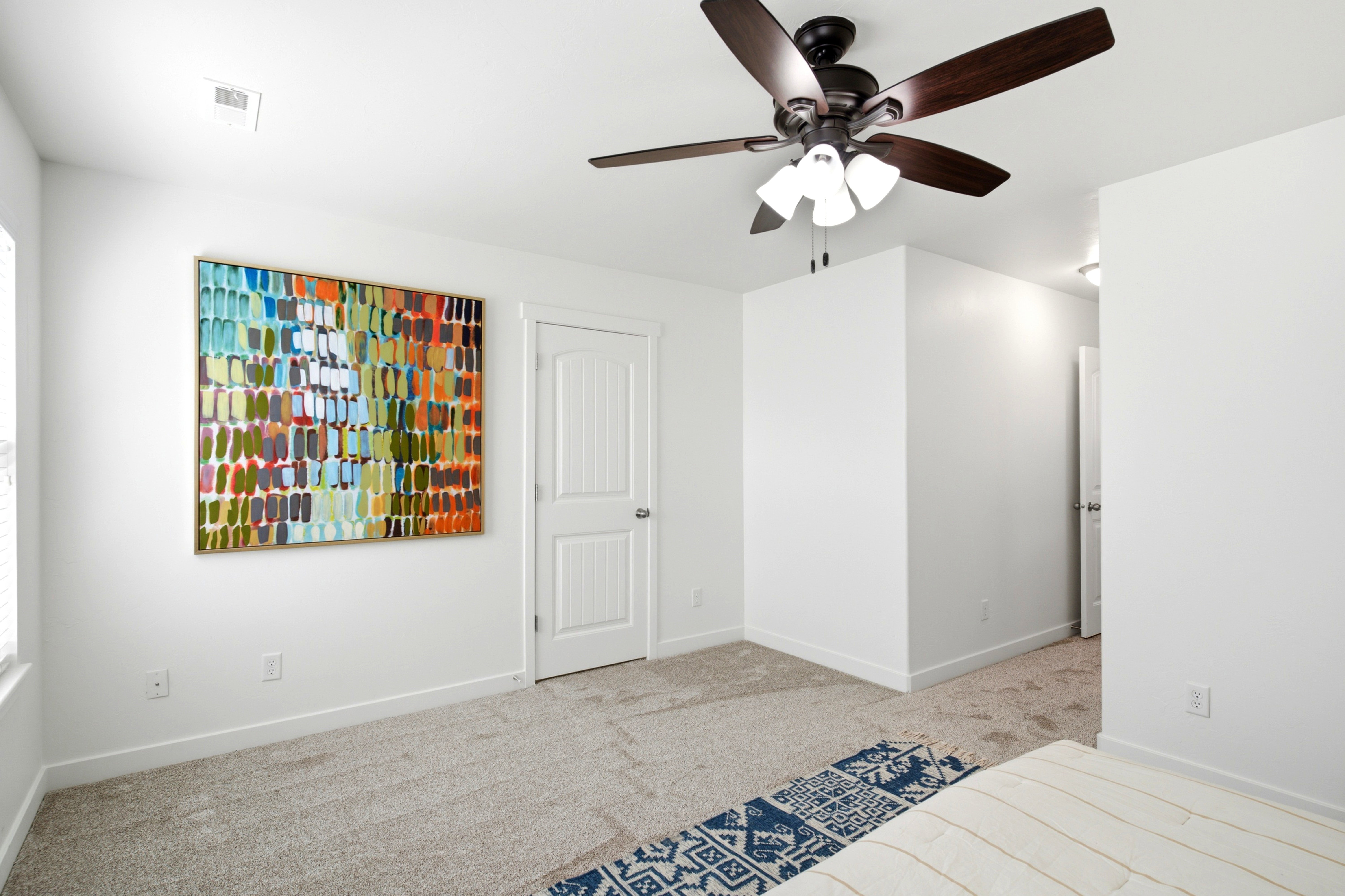 Bedroom featuring neutral carpeting, white walls, and a dark-finished ceiling fan with integrated lighting
