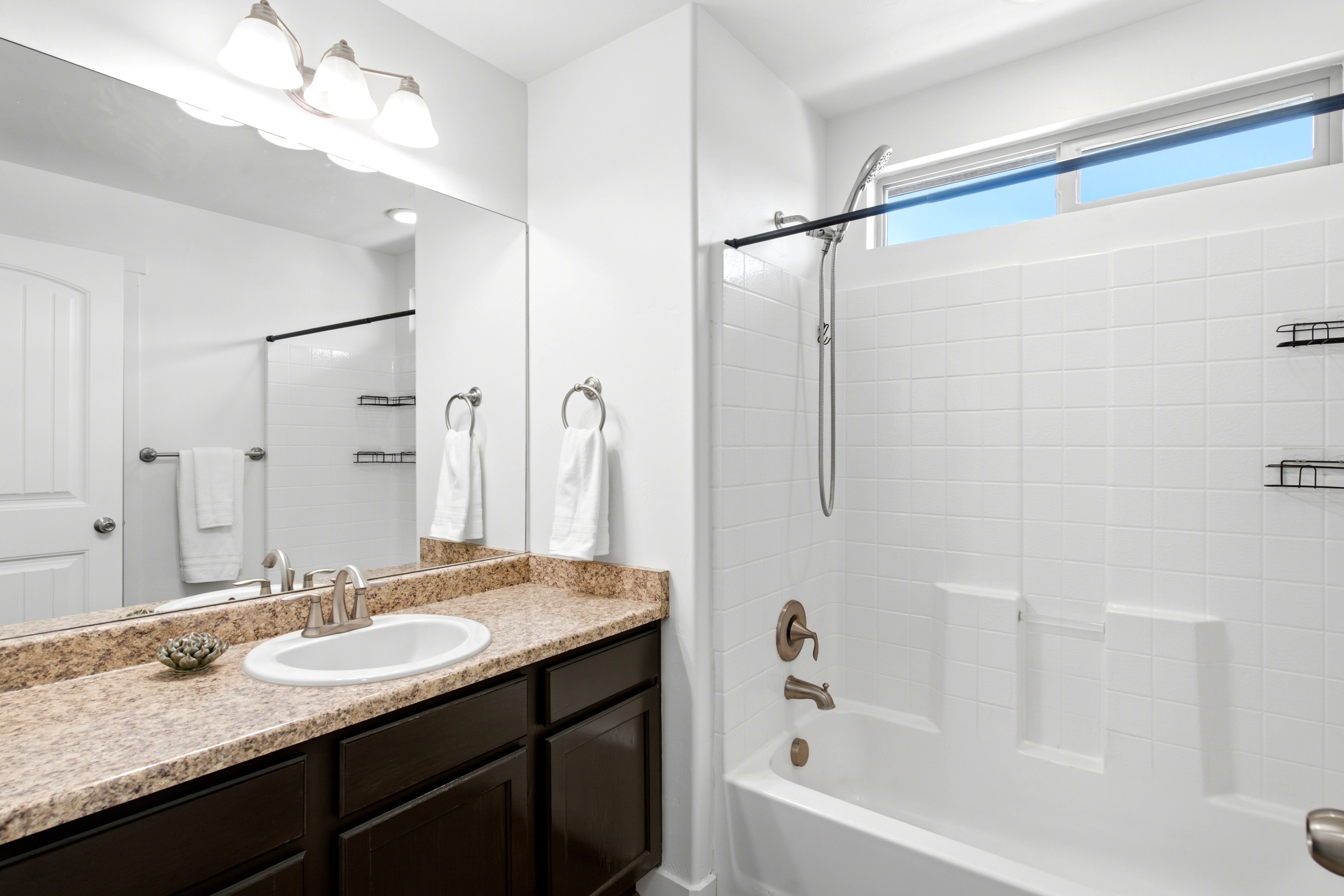 Bathroom featuring a vanity with dark wood-finish cabinetry, a white oval sink, and a speckled countertop