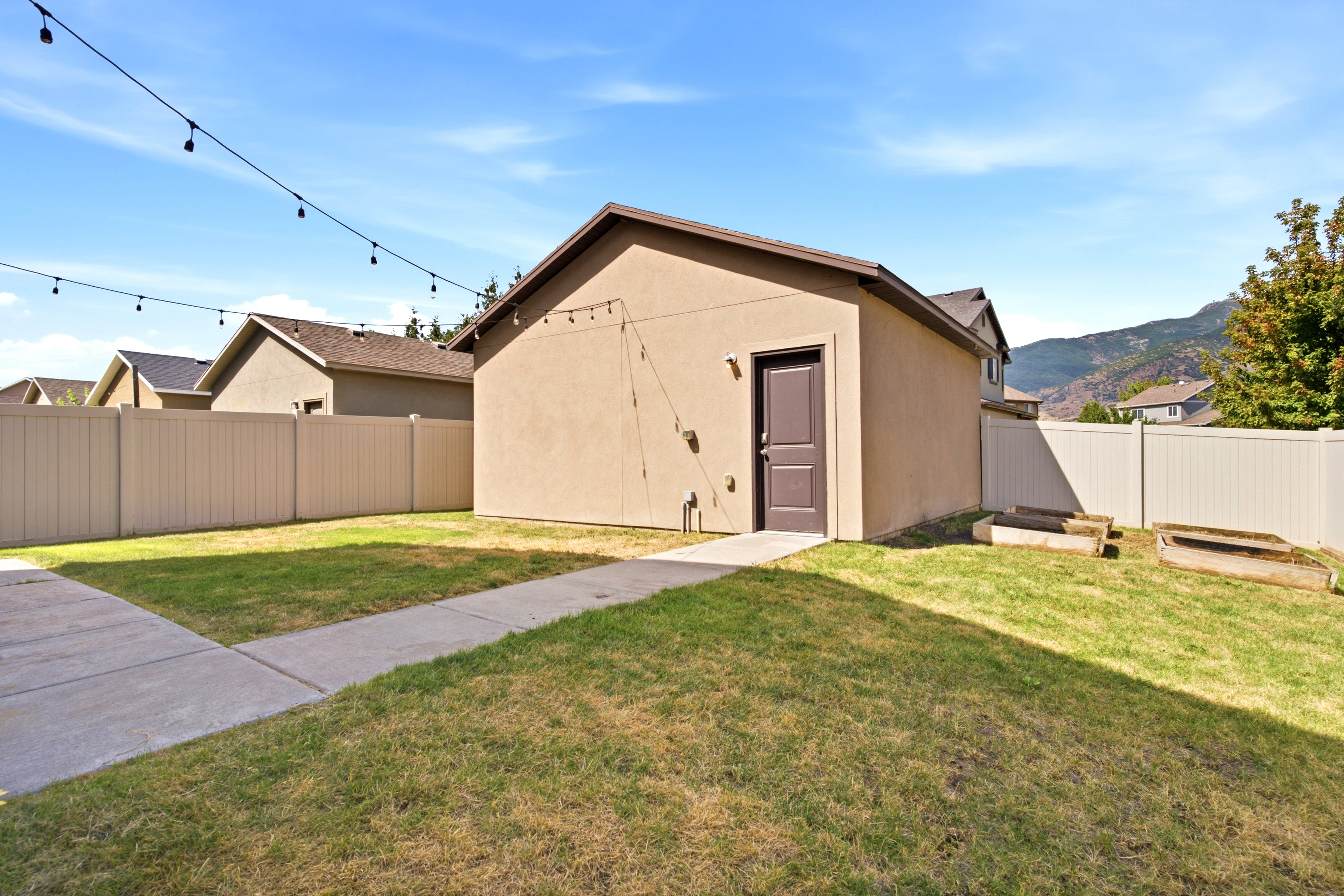 The backyard features a stucco-sided detached structure with a dark brown entry door and shingle roof
