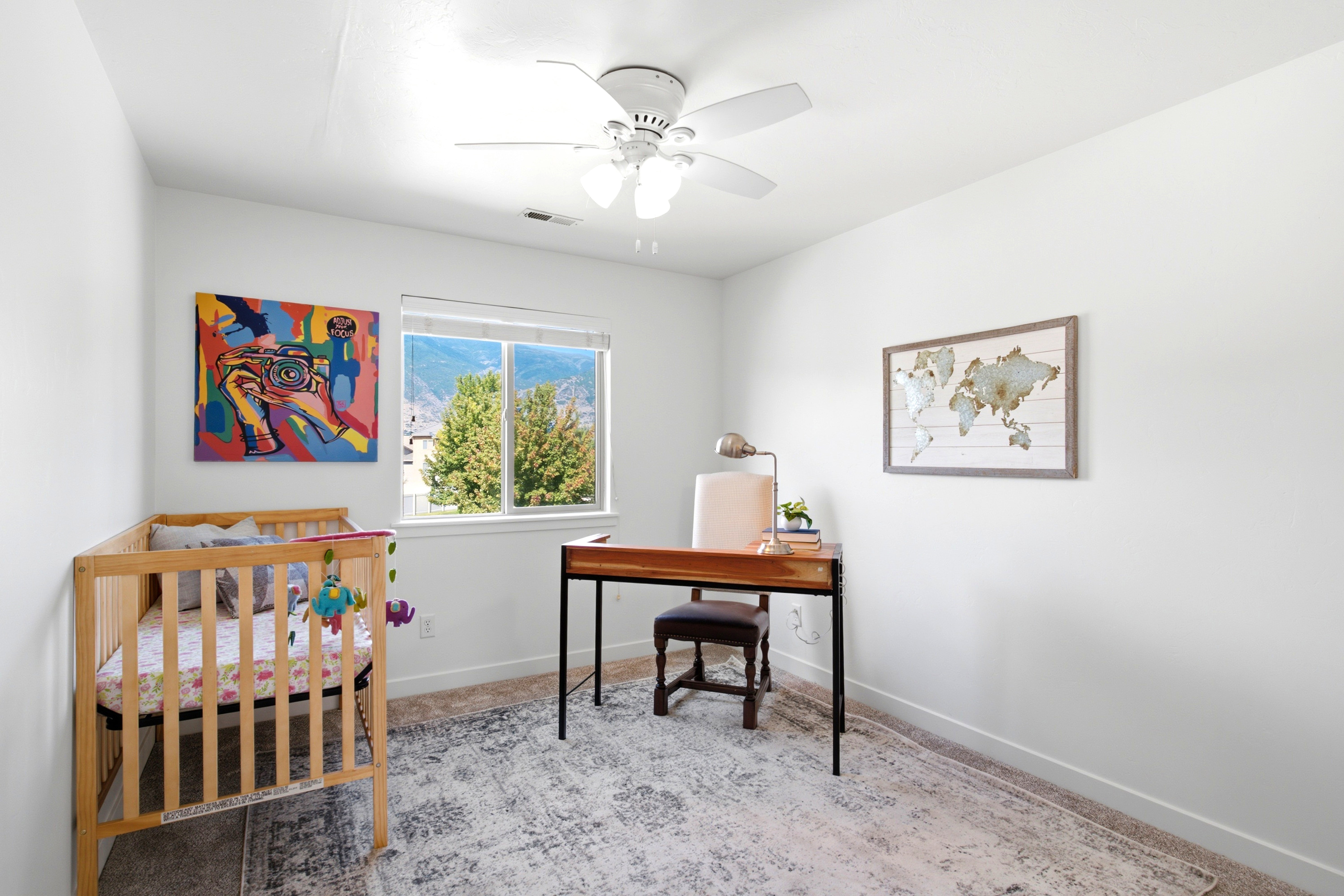 Bright interior room featuring a large window, white walls, and neutral carpet