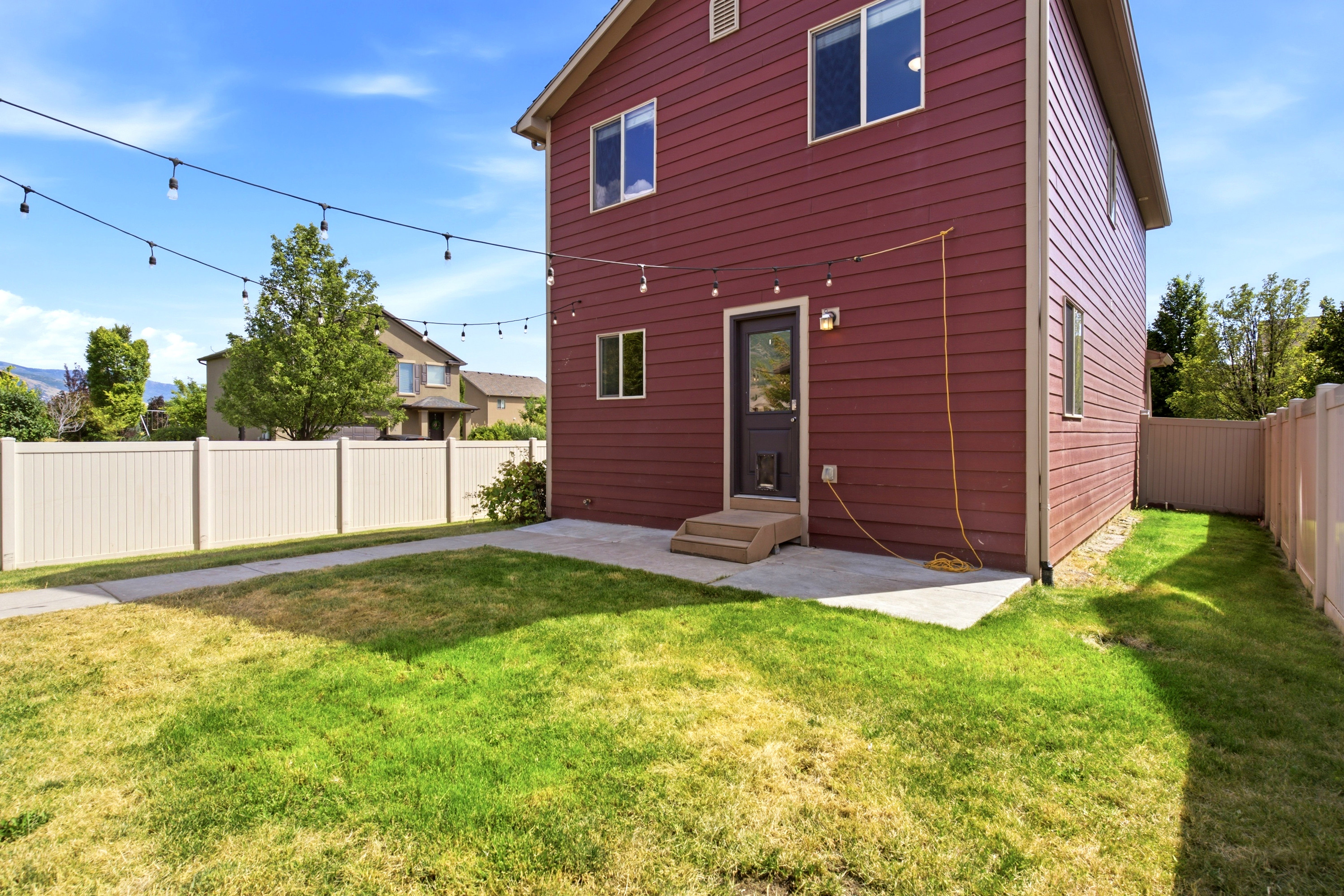 Rear exterior featuring red siding, a private fenced yard, concrete patio, and a direct access door