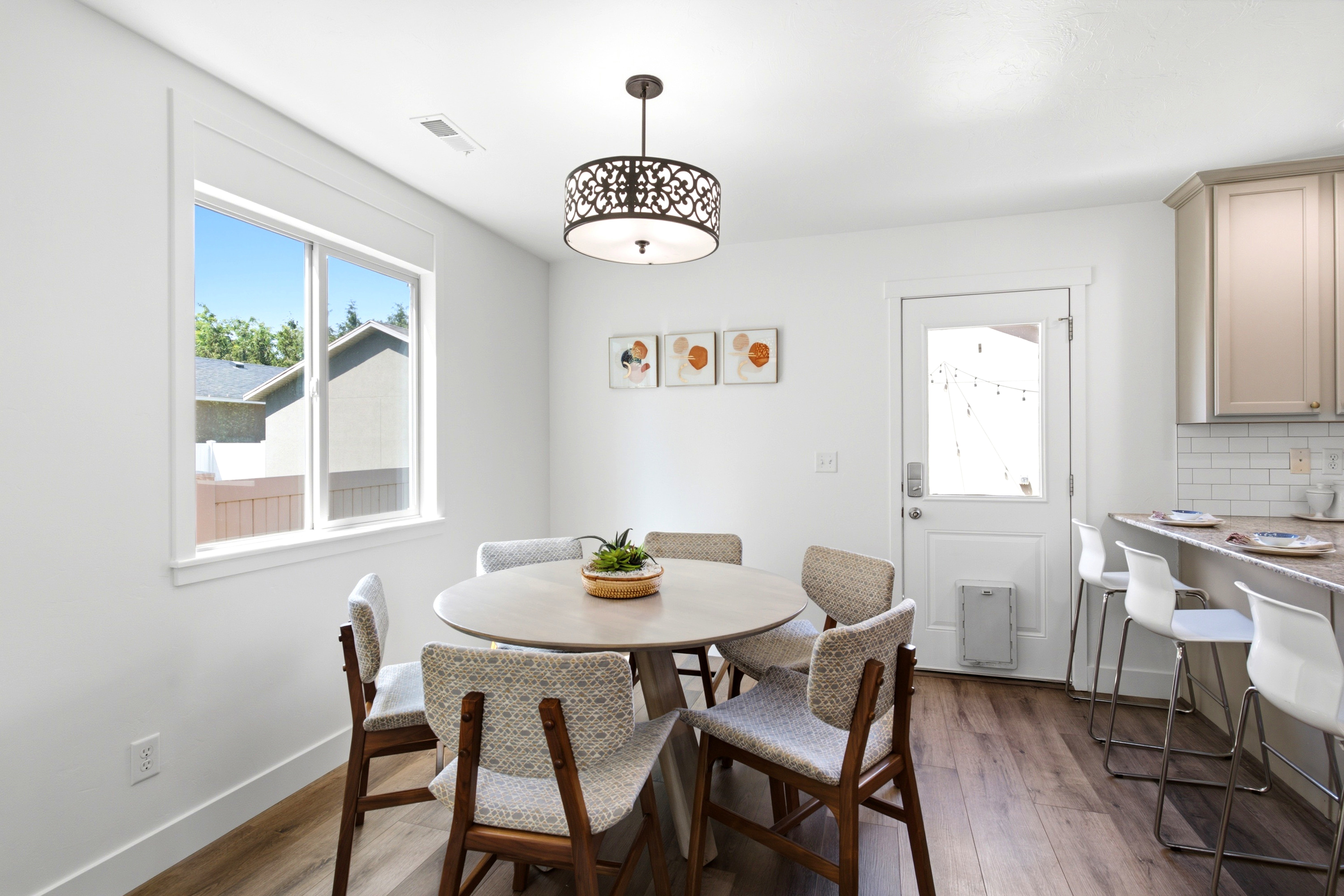 Bright dining area featuring wood-finish flooring, a large window with white trim, and a decorative chandelier