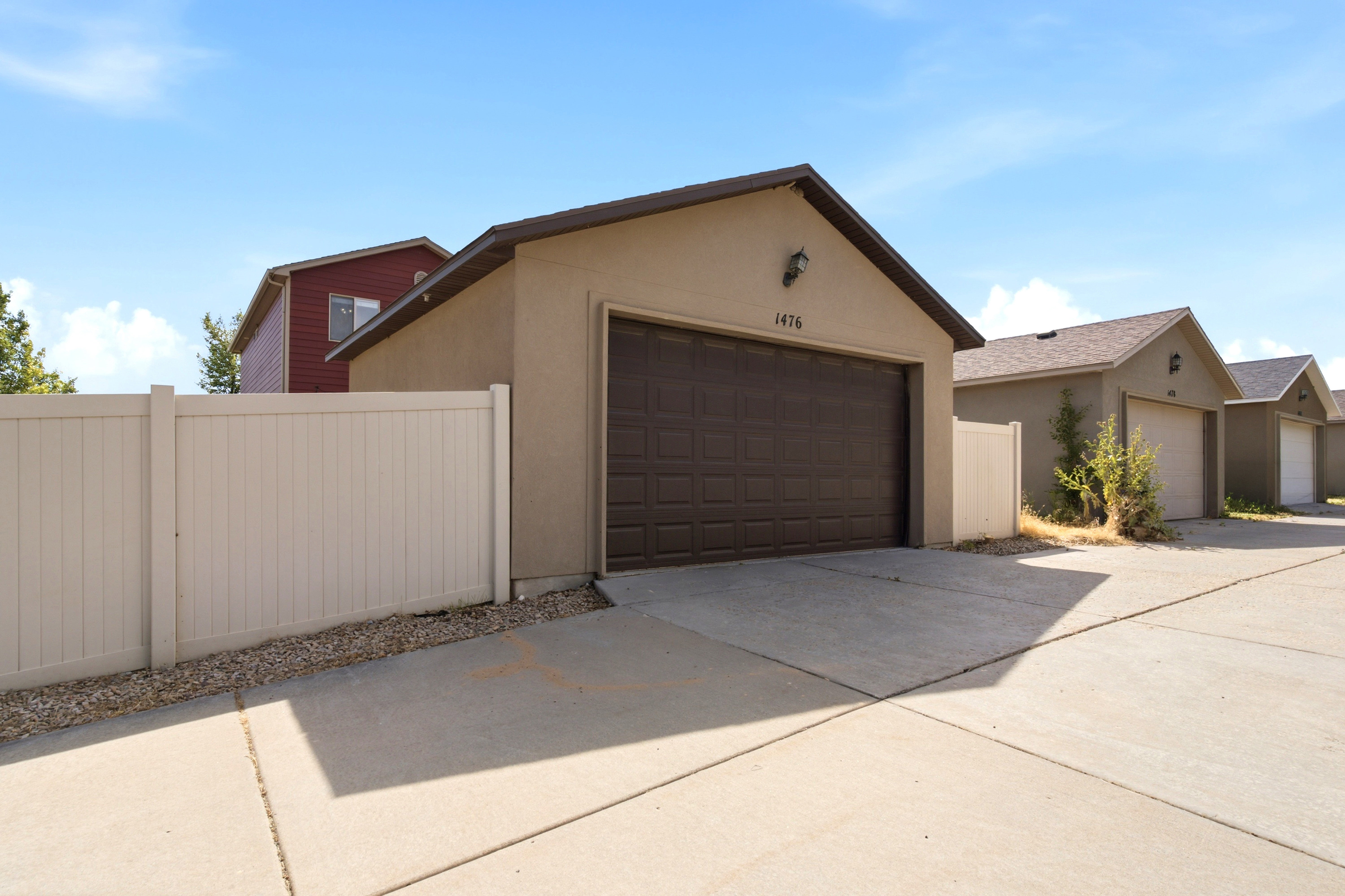 Attached garage featuring a brown sectional door, stucco exterior, and concrete driveway