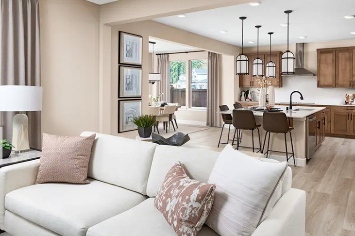 Rendering photo only. Actual finishes may vary. Spacious living area featuring light wood-finish flooring, an open-concept layout, recessed lighting, a kitchen island with seating, and pendant lighting fixtures