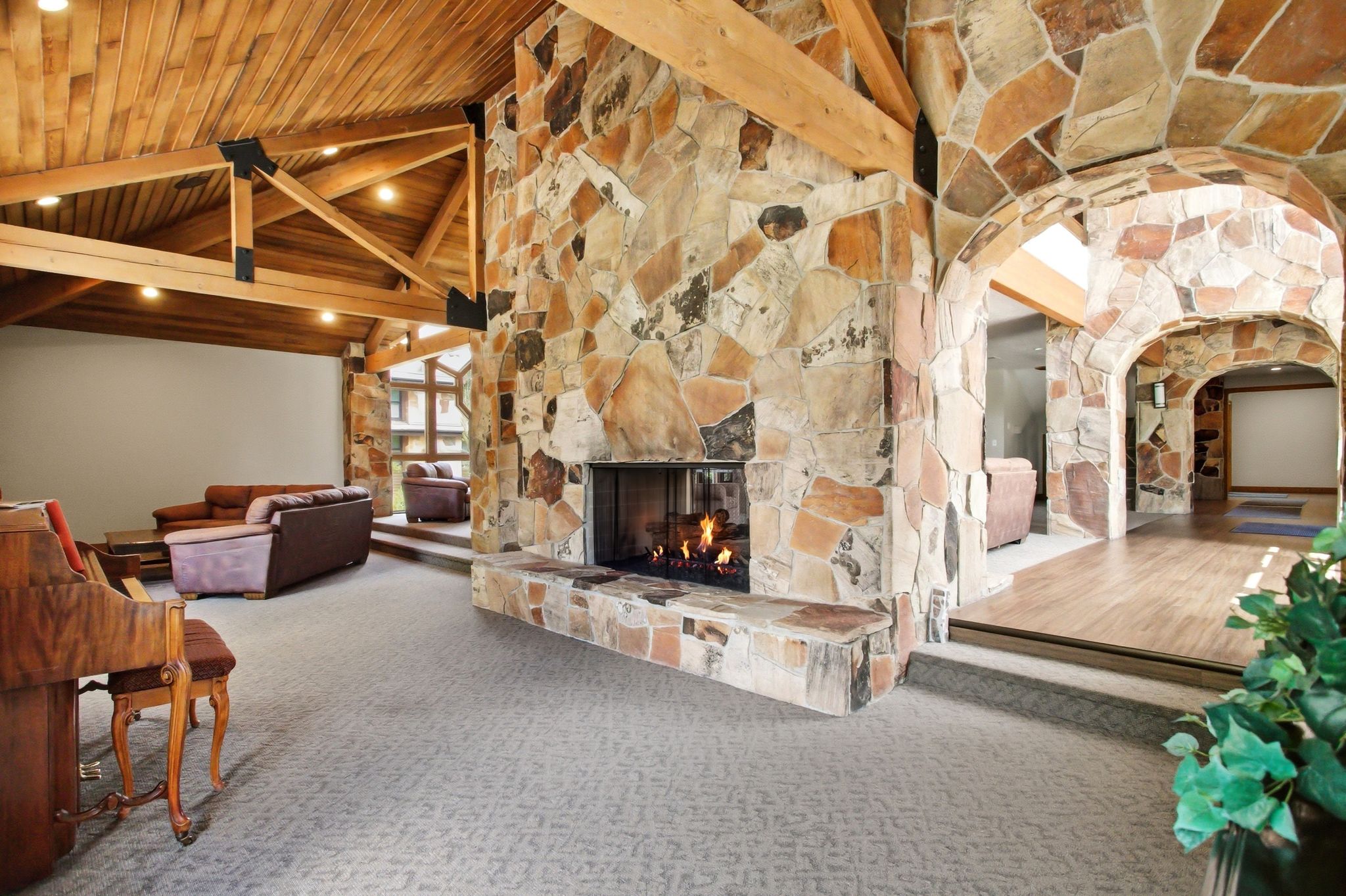 Great room featuring a floor-to-ceiling stone fireplace, vaulted wood-plank ceiling with exposed beams, and recessed lighting