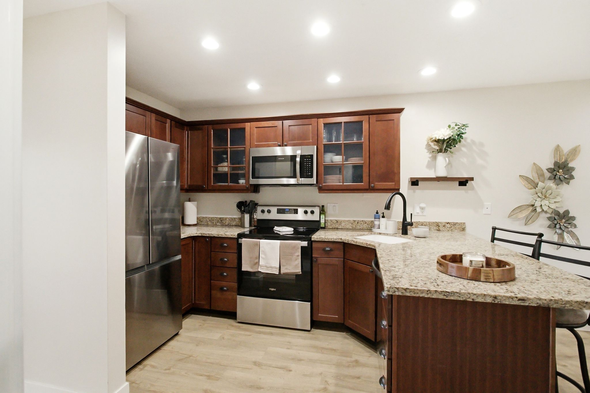 Kitchen featuring wood-finish cabinetry, granite-style countertops, stainless steel appliances, a bar-height counter, and recessed lighting