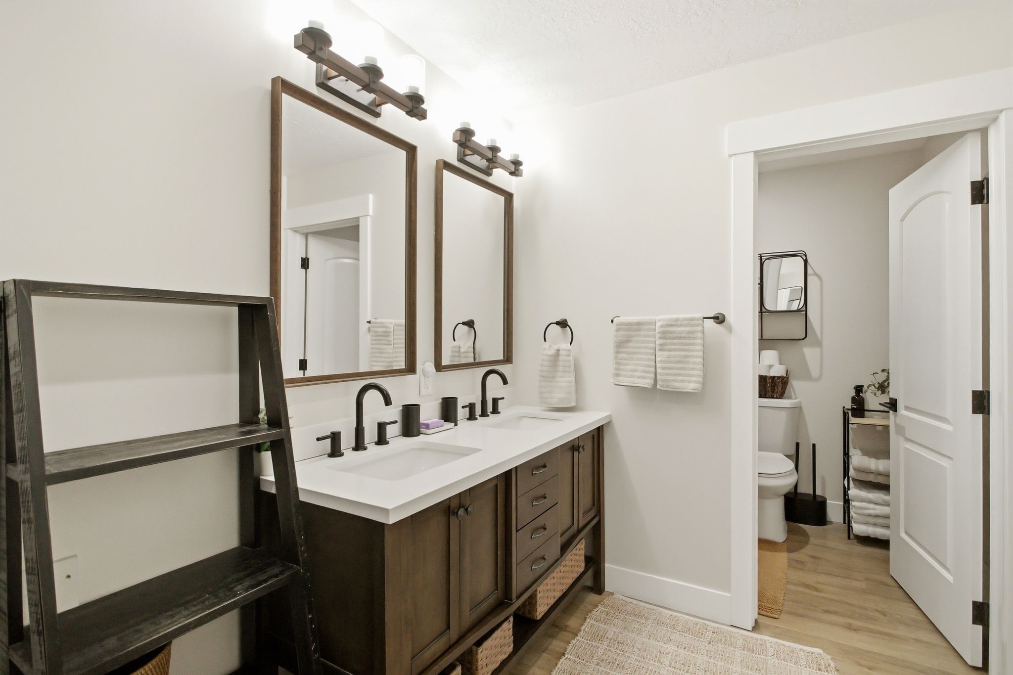 Dual vanity with integrated white sinks, matte black fixtures, and wood-finish cabinetry