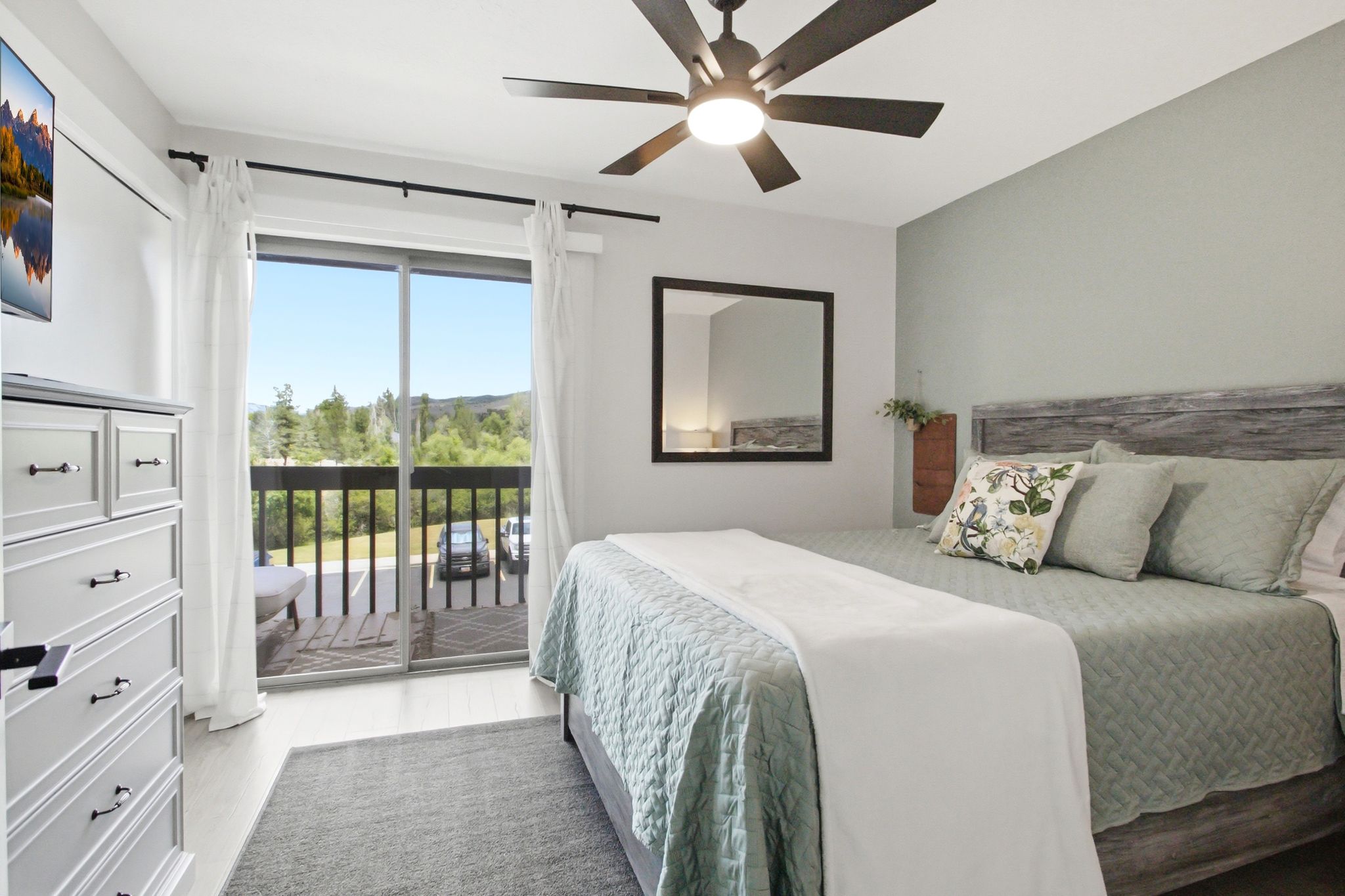 Bedroom featuring wood-finish flooring, a ceiling fan with integrated lighting, and a sliding glass door providing direct access to a private balcony