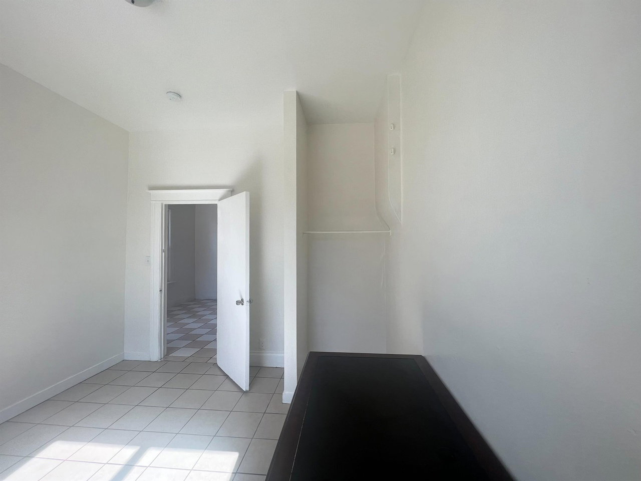 Room featuring light-toned tile flooring, white walls, and a built-in shelf