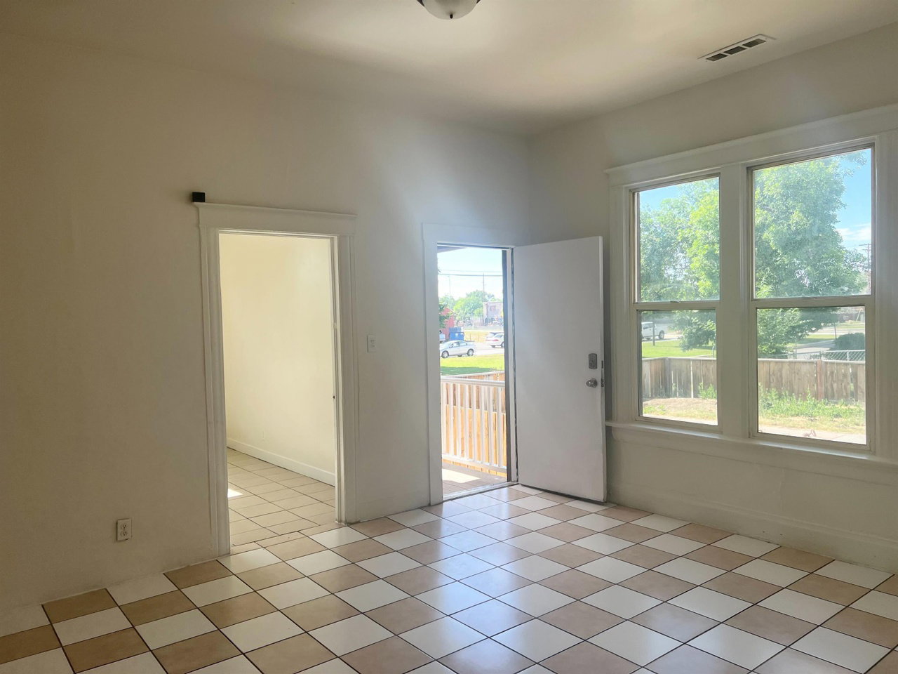 Bright interior space featuring checkerboard tile flooring, white trim, and a three-pane window