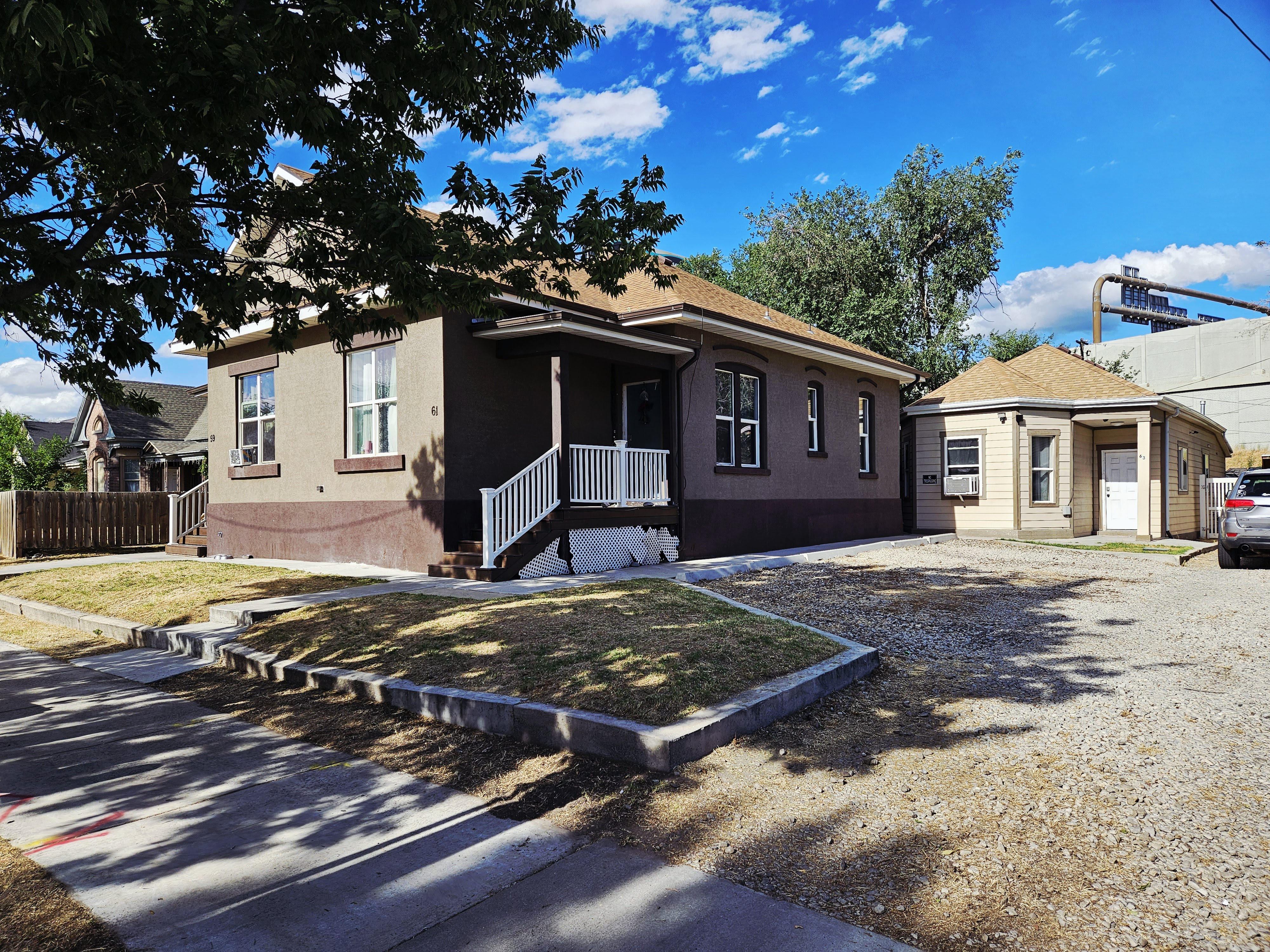 Two-story residence featuring a covered front porch with white railings, a two-tone exterior, and a secondary structure with a gabled roof