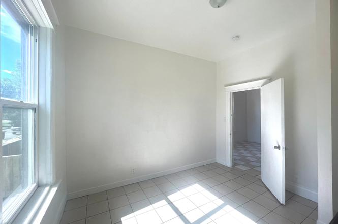 Room featuring a large window, light-toned wall paint, recessed ceiling lighting, and a white tiled floor